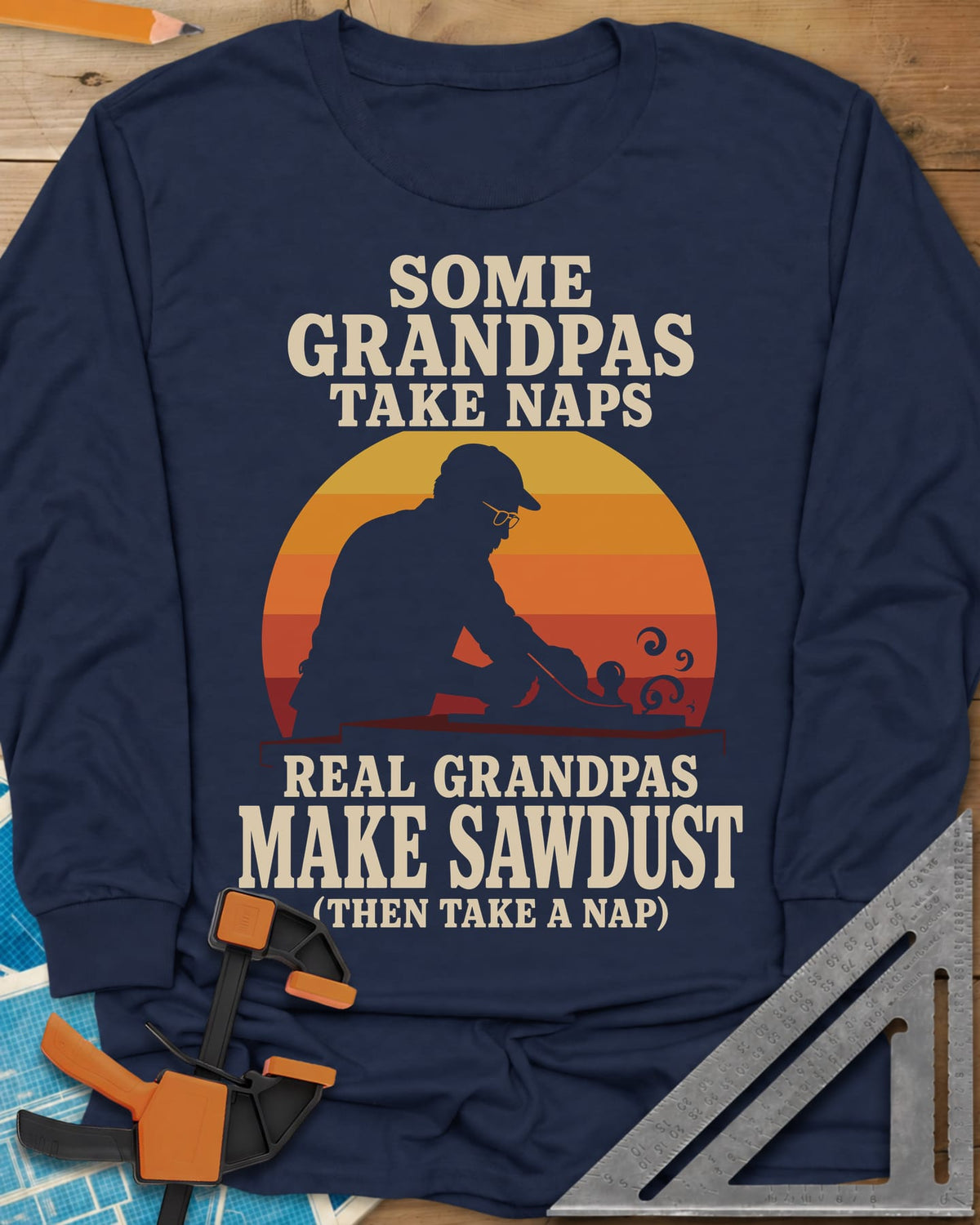 Real Grandpas Make Sawdust long sleeve shirt in Navy, striped sunset circle behind a cap-wearing grandpa planing a board