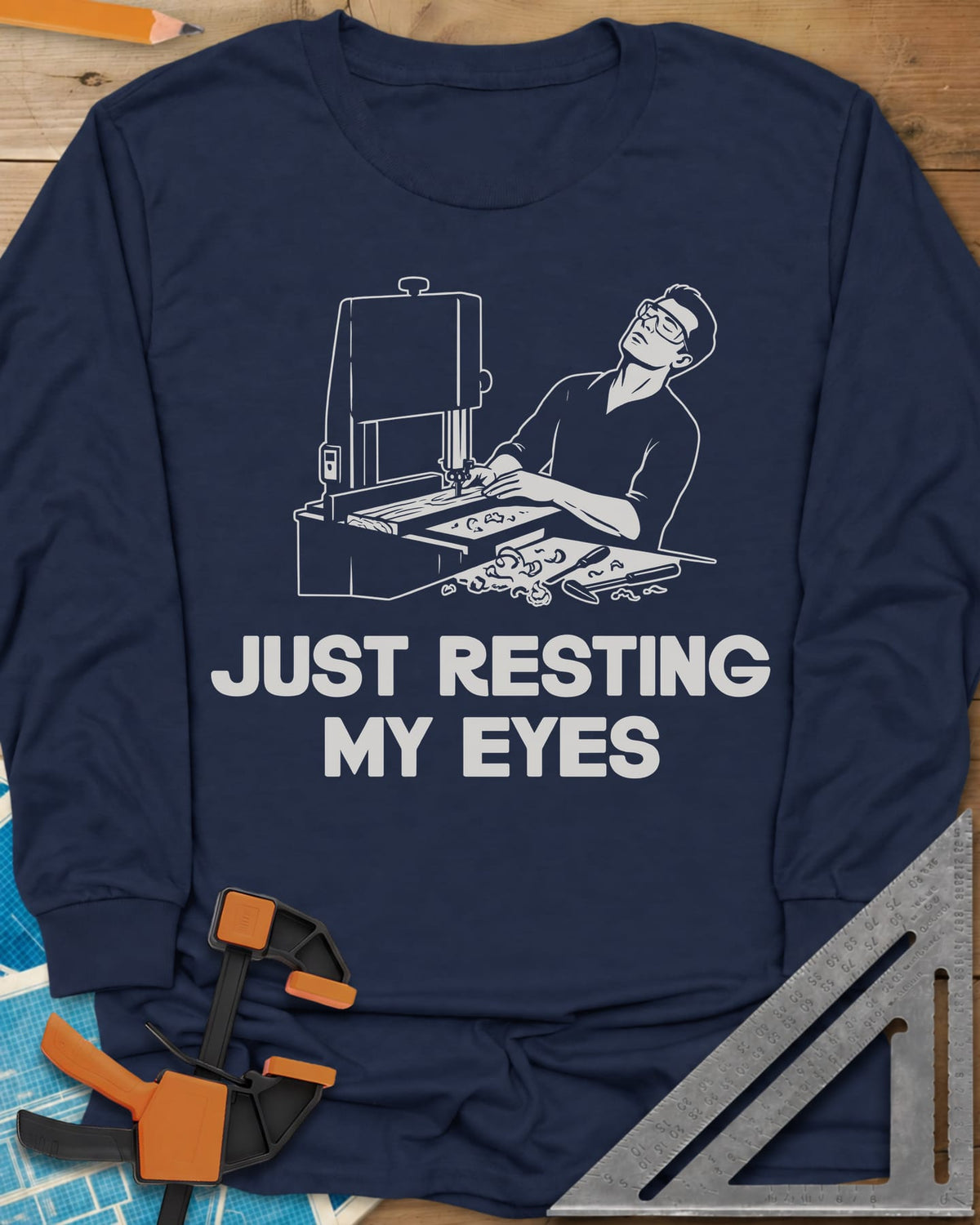 Resting My Eyes long sleeve shirt in Navy, man in safety glasses tipped back at a band saw, shavings on the bench