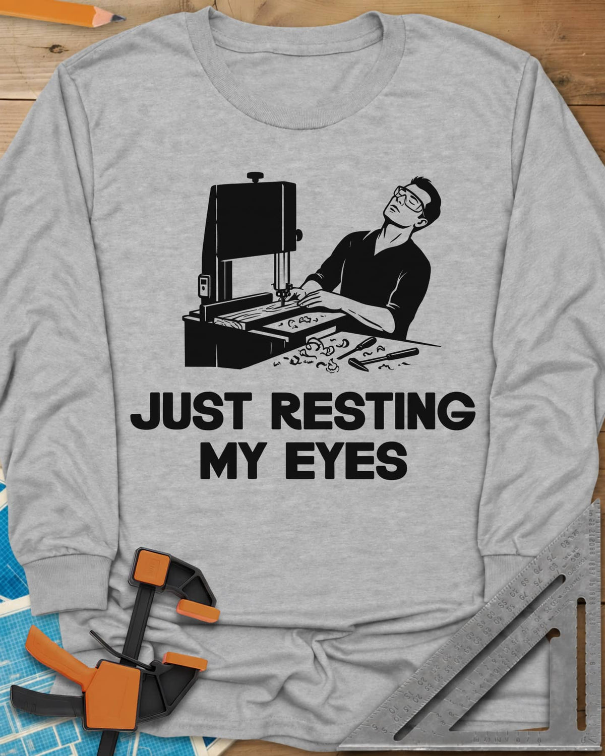 Resting My Eyes long sleeve shirt in Sport Grey, man in safety glasses tipped back at a band saw, shavings on the bench