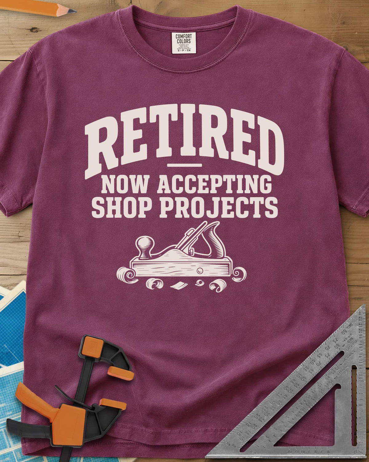 Retired Projects heavyweight tee in Berry, a hand plane with curled shavings under varsity RETIRED lettering
