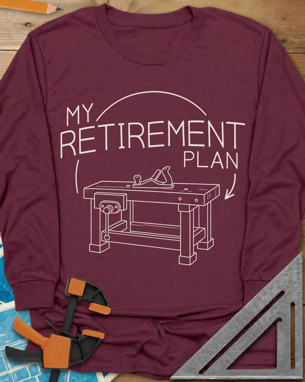 Retirement Plan long sleeve shirt in Maroon, line drawing of a woodworking bench with a vise and hand plane