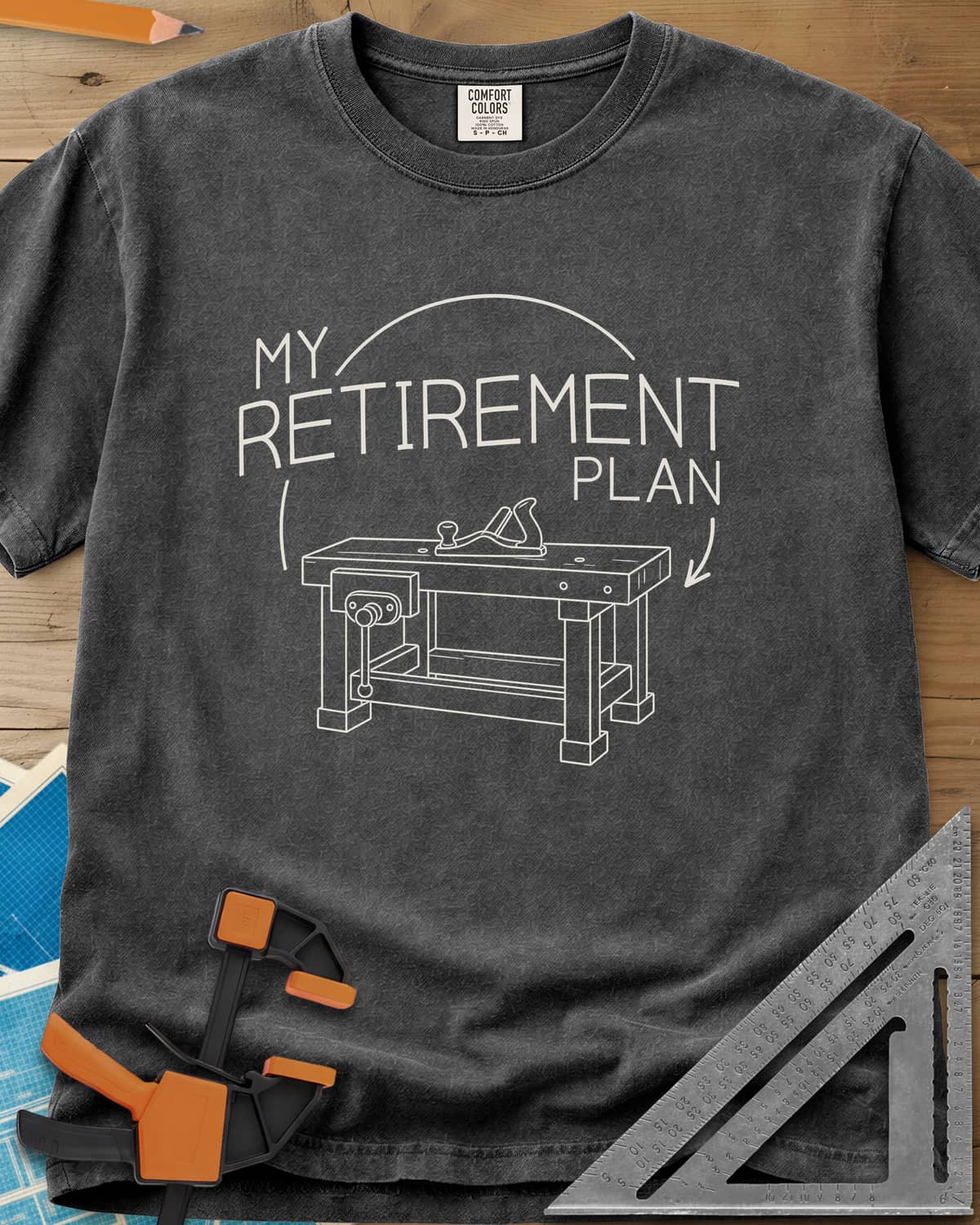 Retirement Plan heavyweight tee in Pepper, line drawing of a woodworking bench with a vise and hand plane