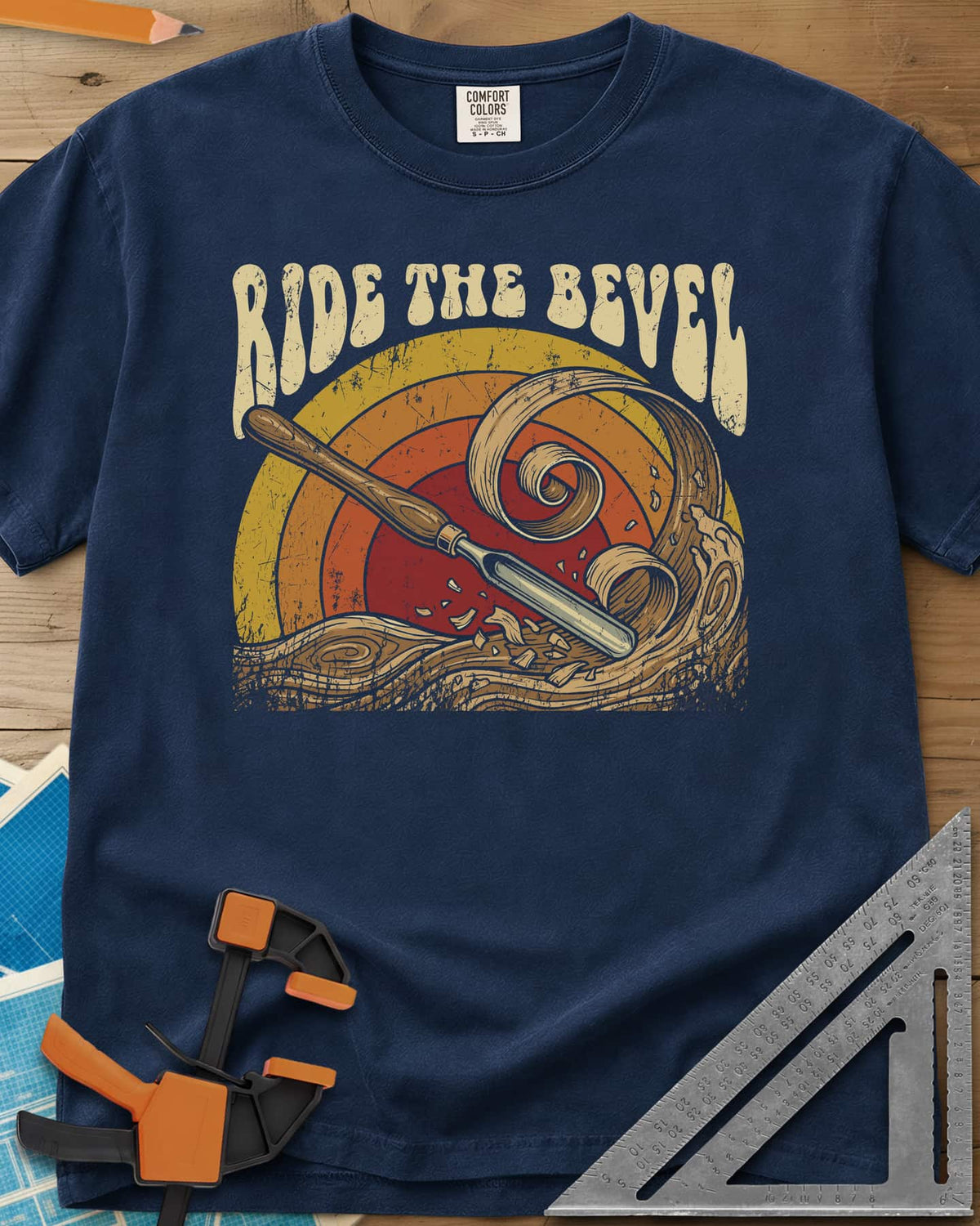 Ride The Bevel heavyweight tee in Navy, a carving gouge riding a wave of wood curls under a retro sunset