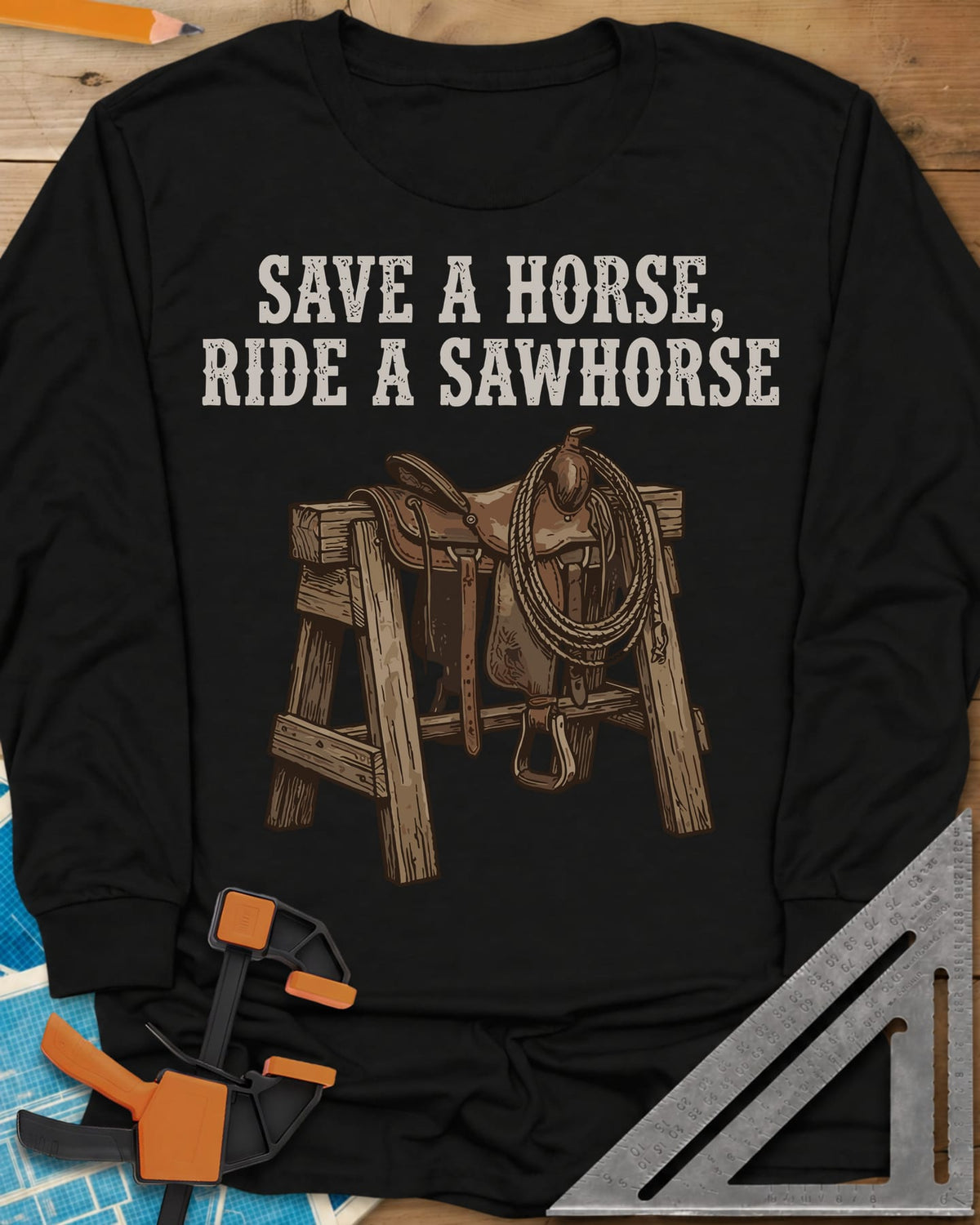 Save a Horse long sleeve shirt in Black, a western saddle and lasso rope draped over a wooden sawhorse