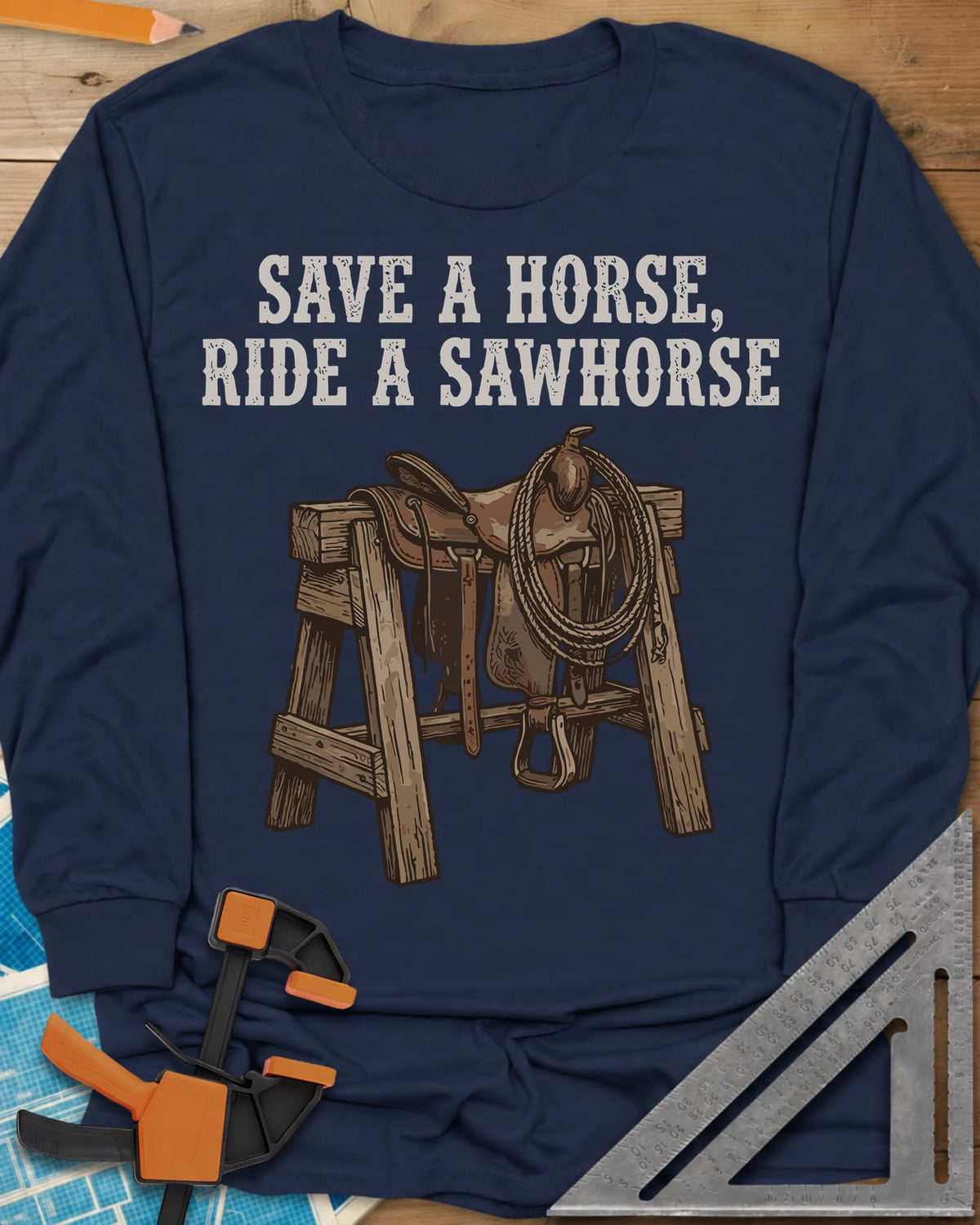 Save a Horse long sleeve shirt in Navy, a western saddle and lasso rope draped over a wooden sawhorse