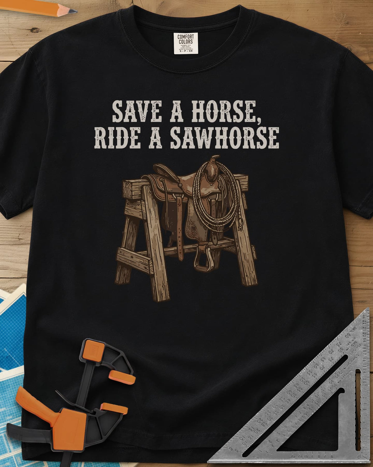 Save a Horse heavyweight tee in Black, a western saddle and lasso rope draped over a wooden sawhorse