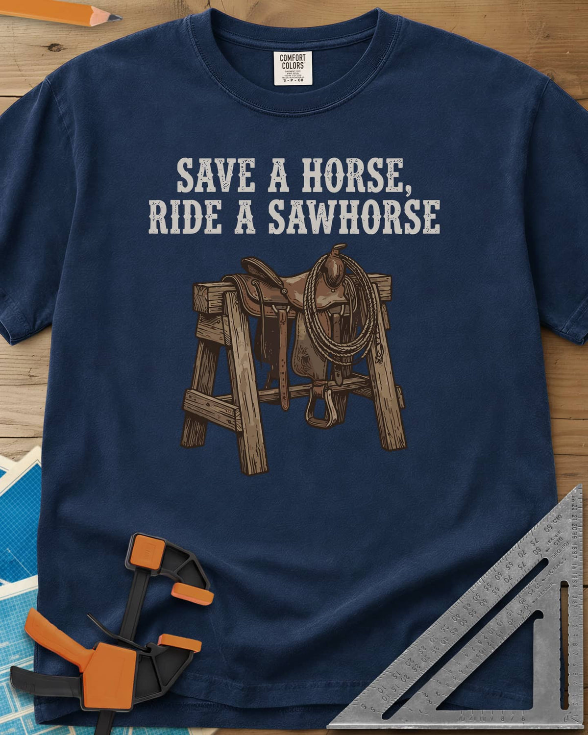 Save a Horse heavyweight tee in Navy, a western saddle and lasso rope draped over a wooden sawhorse