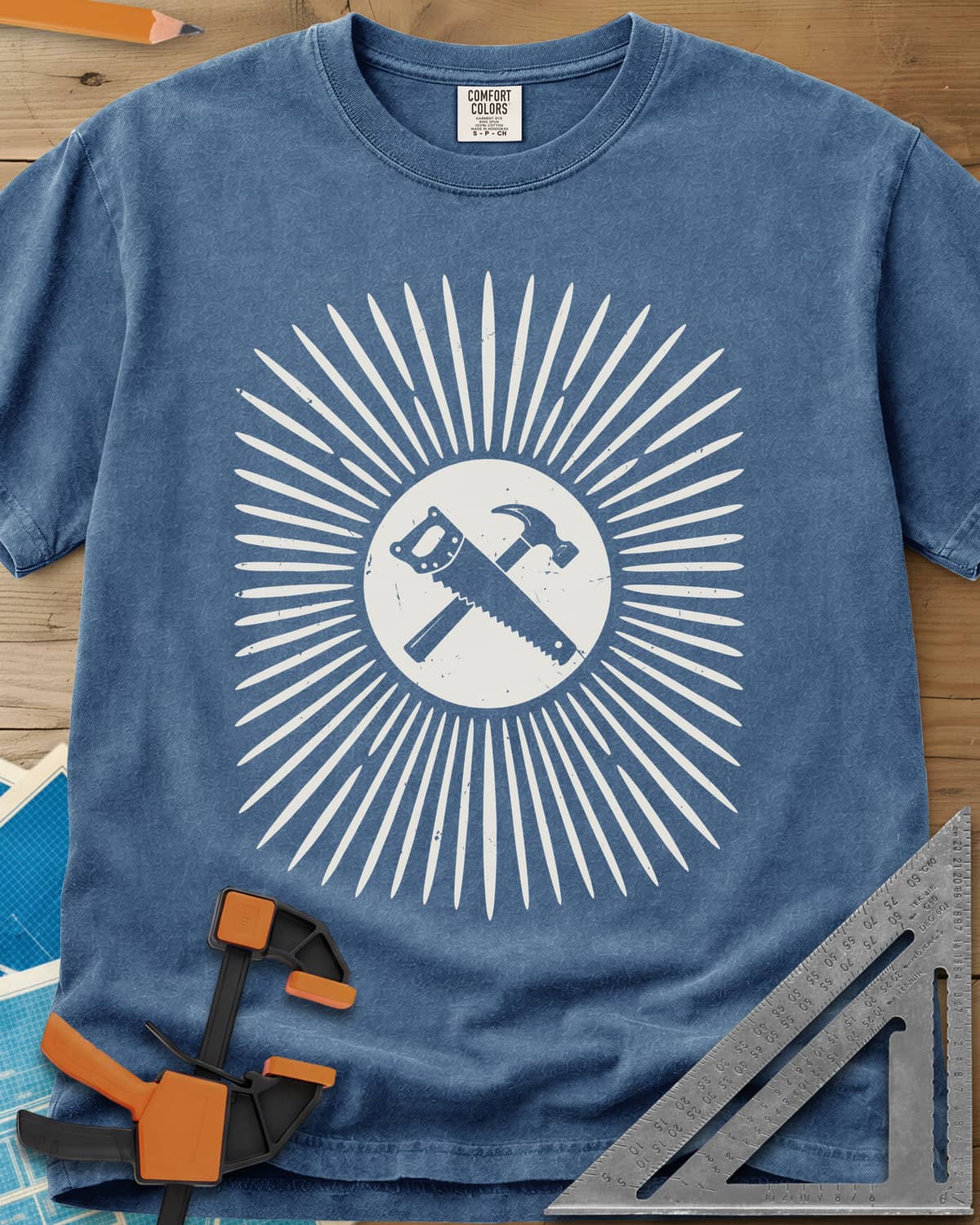 Saw & Hammer heavyweight tee in Blue Jean, crossed handsaw and hammer on a rust circle in a sunburst of rays