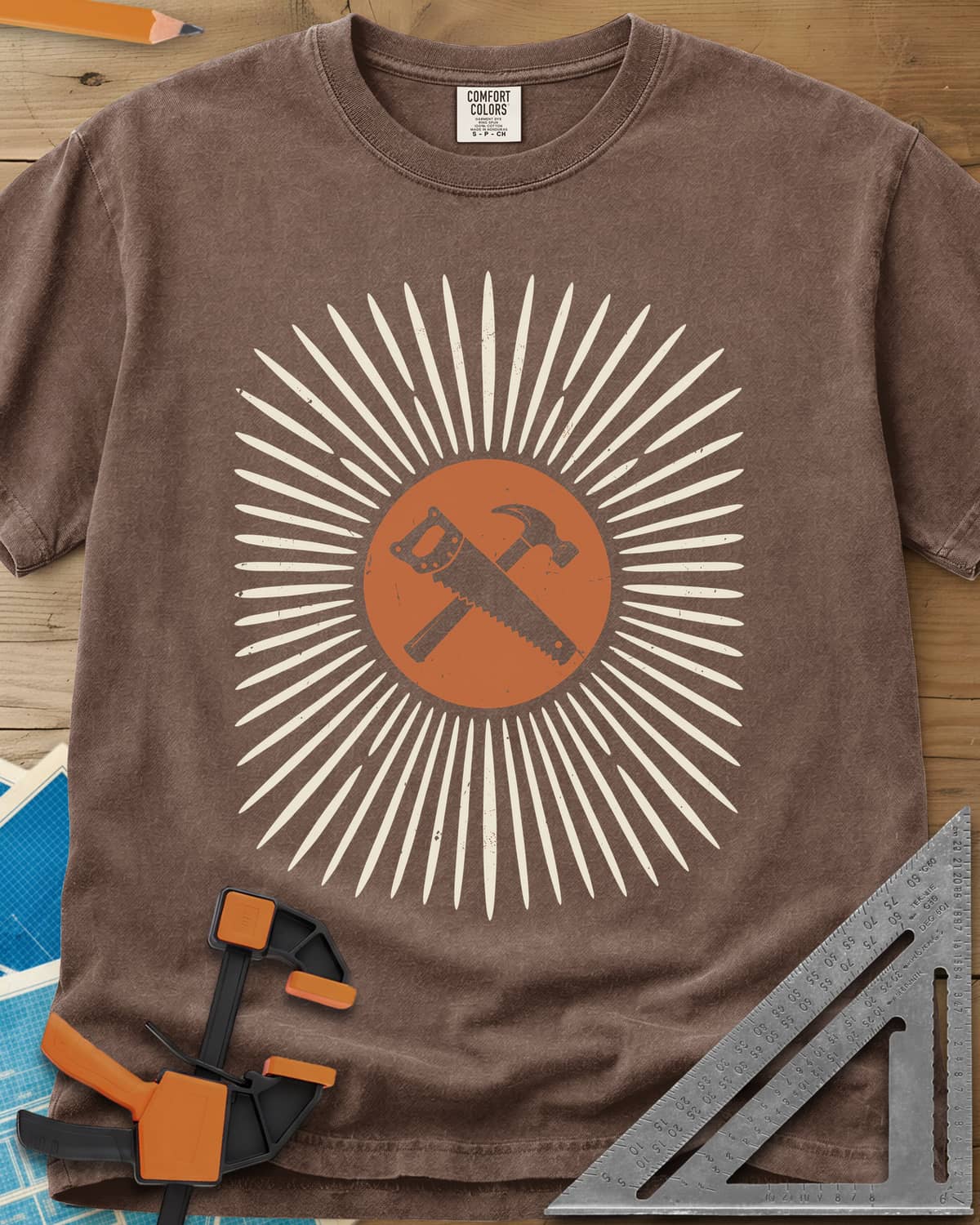 Saw & Hammer heavyweight tee in Espresso, crossed handsaw and hammer on a rust circle in a sunburst of rays