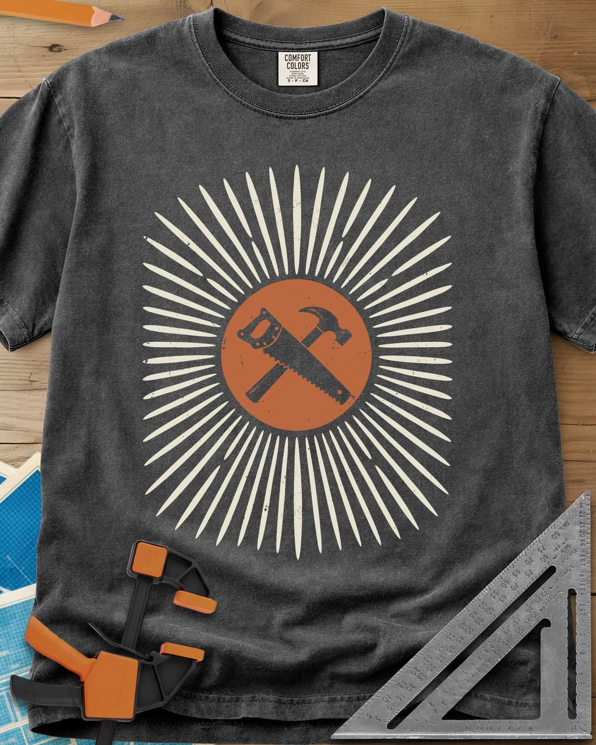 Saw & Hammer heavyweight tee in Pepper, crossed handsaw and hammer on a rust circle in a sunburst of rays
