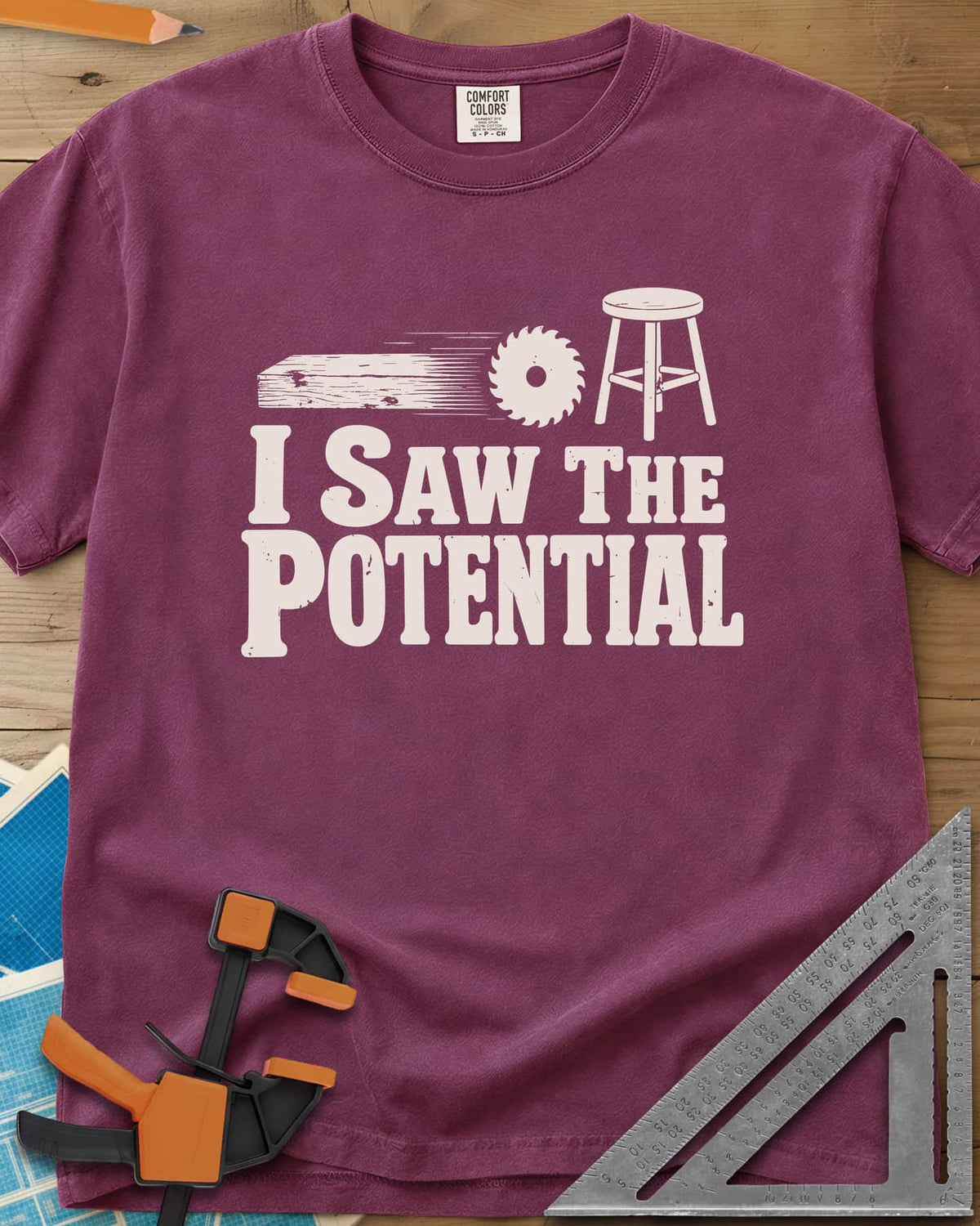 Saw The Potential heavyweight tee in Berry, a speeding plank, a saw blade and a finished stool