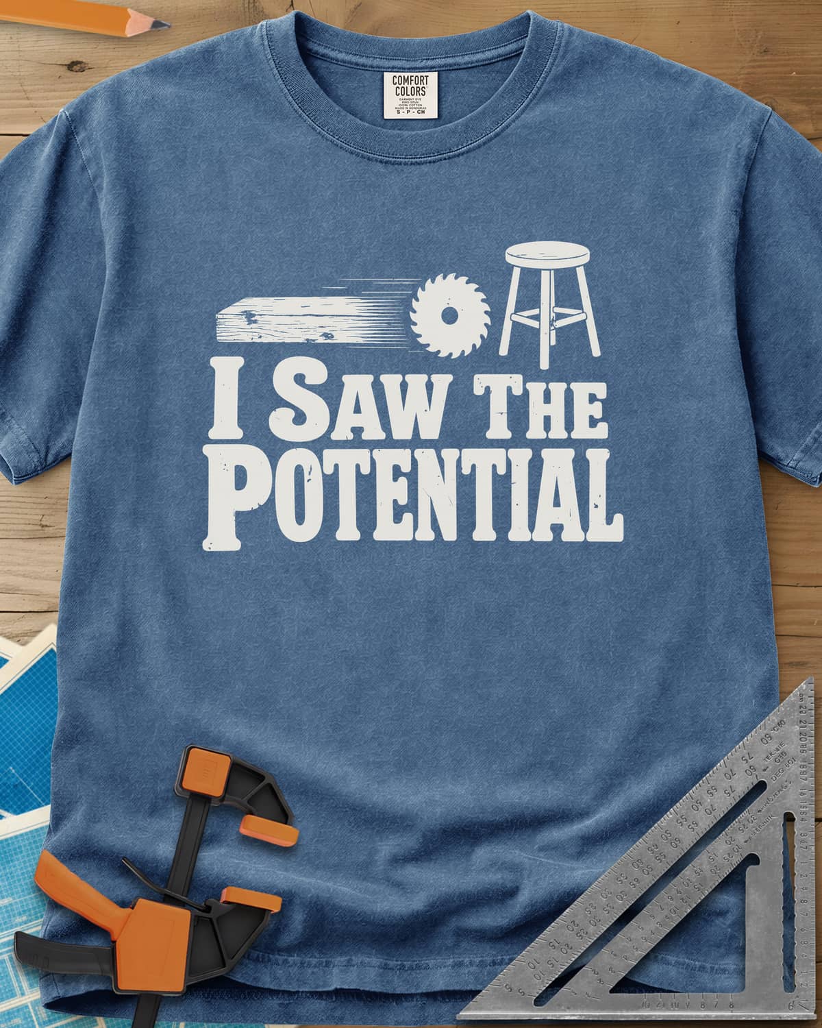 Saw The Potential heavyweight tee in Blue Jean, a speeding plank, a saw blade and a finished stool