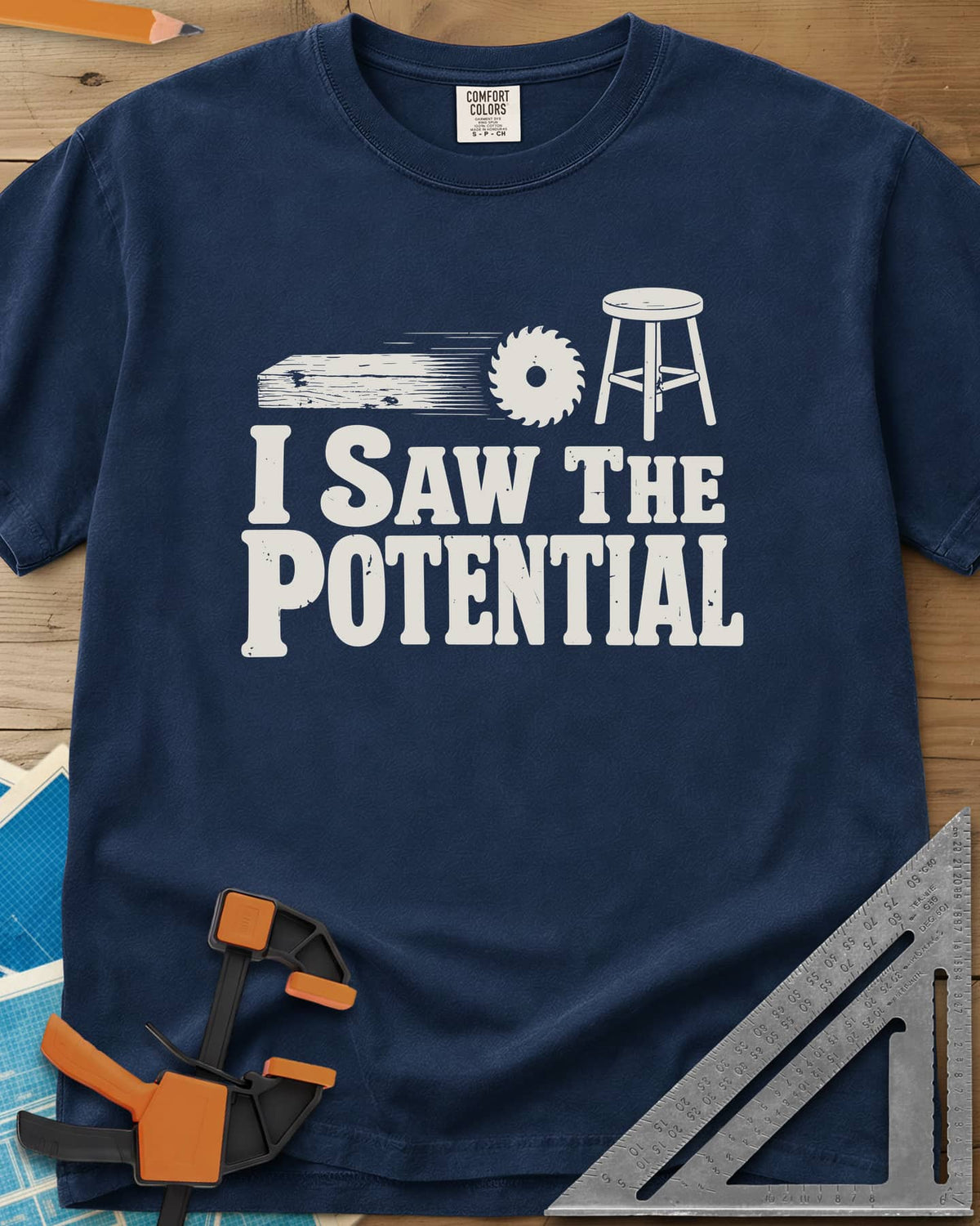 Saw The Potential heavyweight tee in Navy, a speeding plank, a saw blade and a finished stool