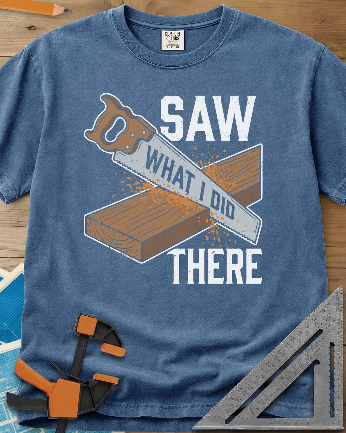 Saw What I Did heavyweight tee in Blue Jean, a hand saw cutting a plank with WHAT I DID lettered on its blade