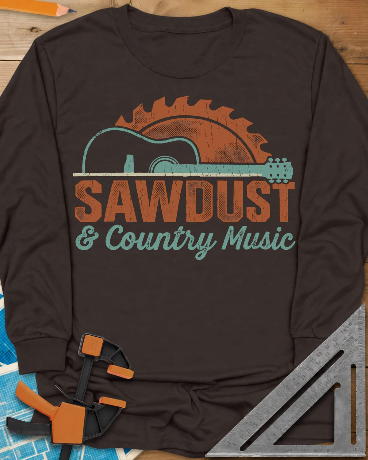 Sawdust And Country Music long sleeve shirt in Dark Chocolate, an acoustic guitar in front of a rising saw blade