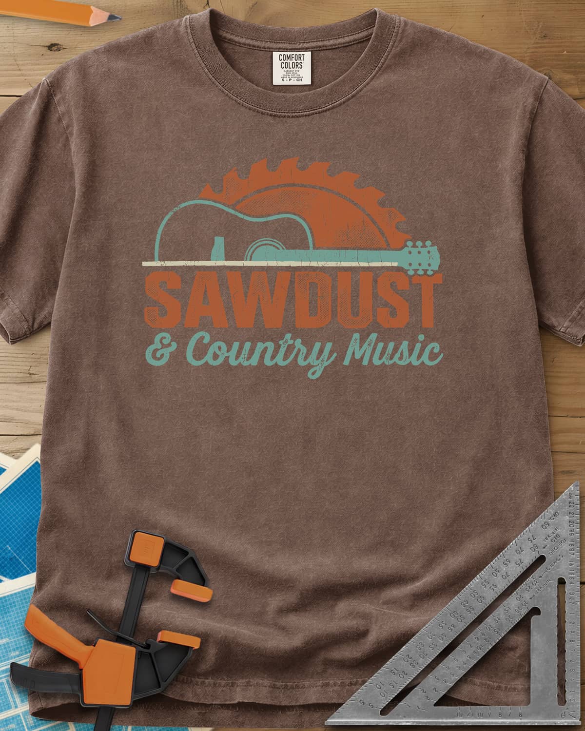 Sawdust And Country Music heavyweight tee in Espresso, an acoustic guitar in front of a rising saw blade
