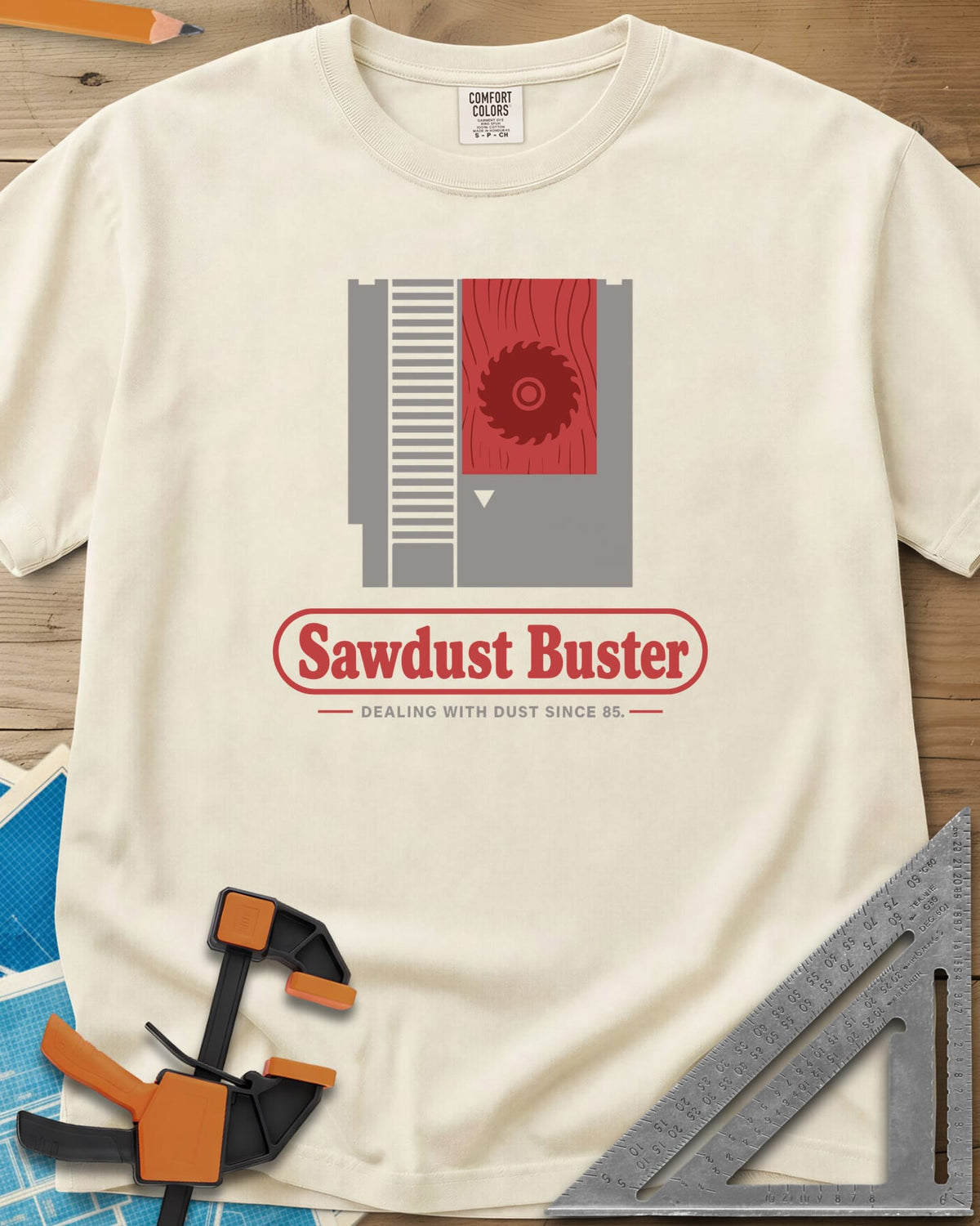 Sawdust Buster heavyweight tee in Ivory, retro game cartridge with a saw blade on a red wood-grain label