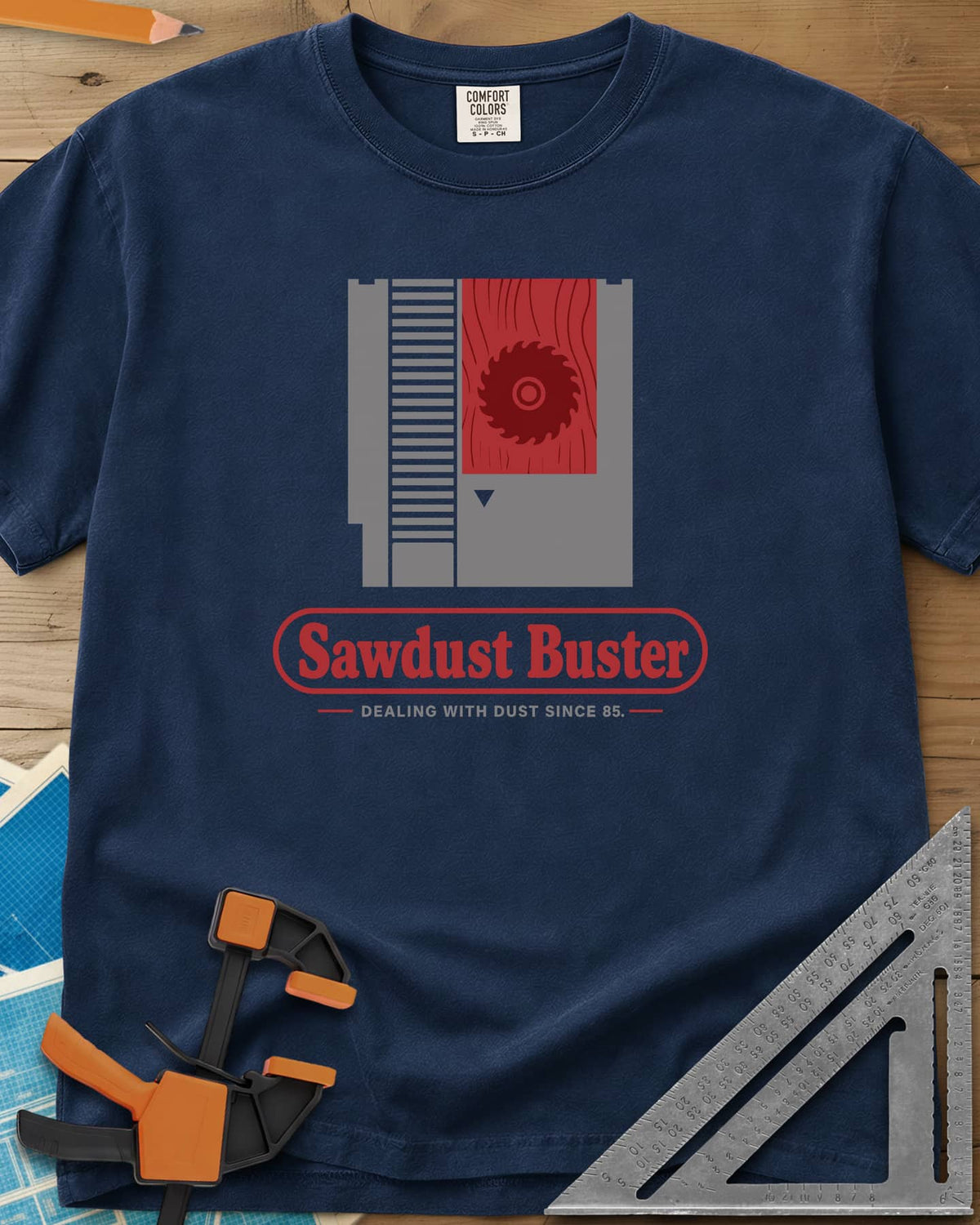 Sawdust Buster heavyweight tee in Navy, retro game cartridge with a saw blade on a red wood-grain label