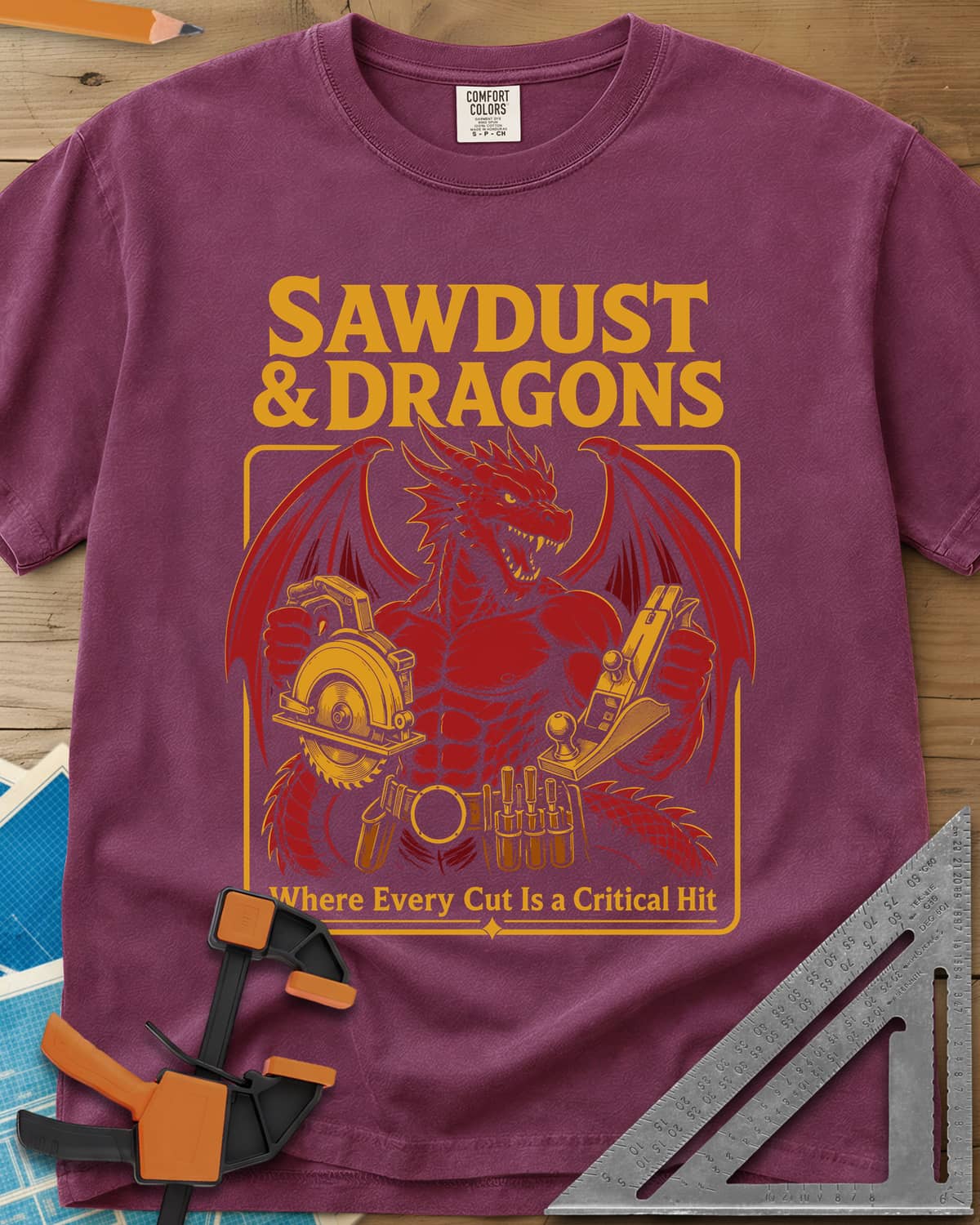 Sawdust & Dragons heavyweight tee in Berry, red dragon in a tool belt holding a circular saw and a hand plane