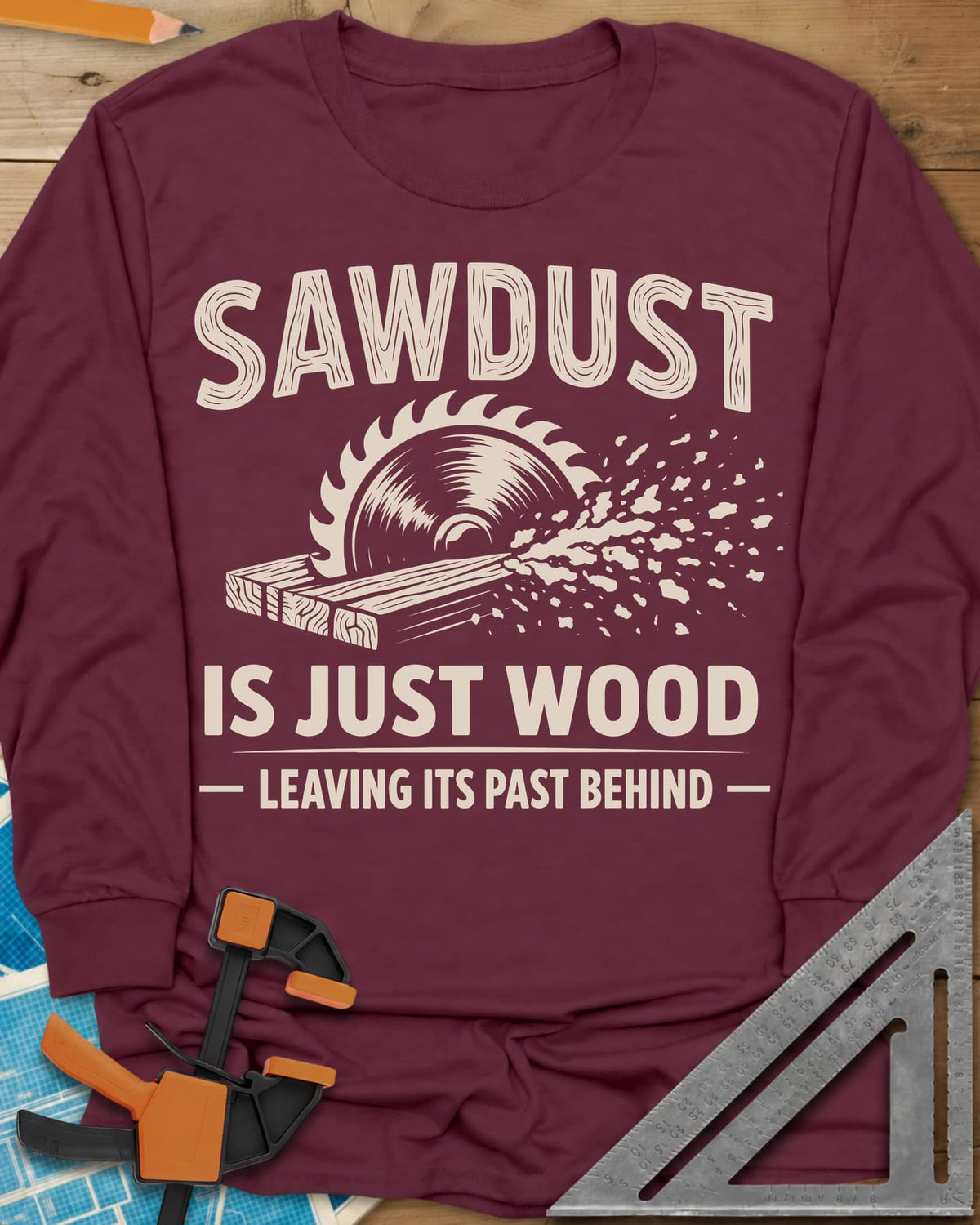 Sawdust Leaving Its Past Behind long sleeve shirt in Maroon, wood-grain lettering above a circular saw cutting a board