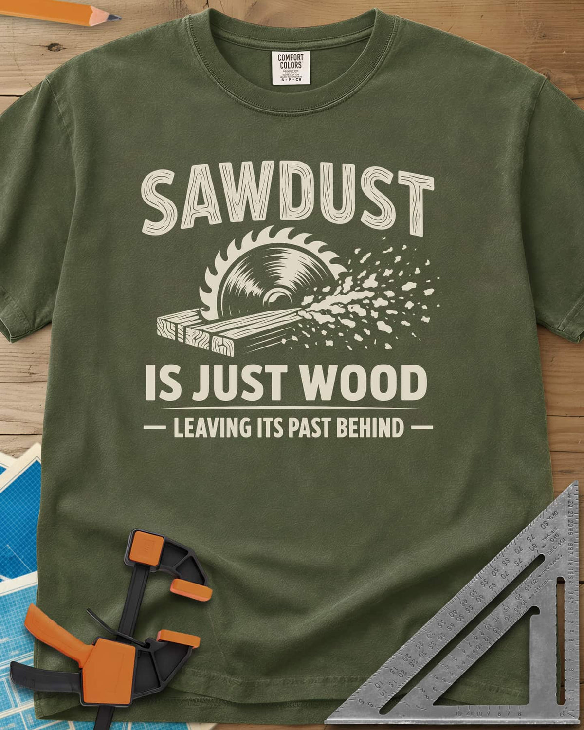 Sawdust Leaving Its Past Behind heavyweight tee in Hemp, wood-grain lettering above a circular saw cutting a board