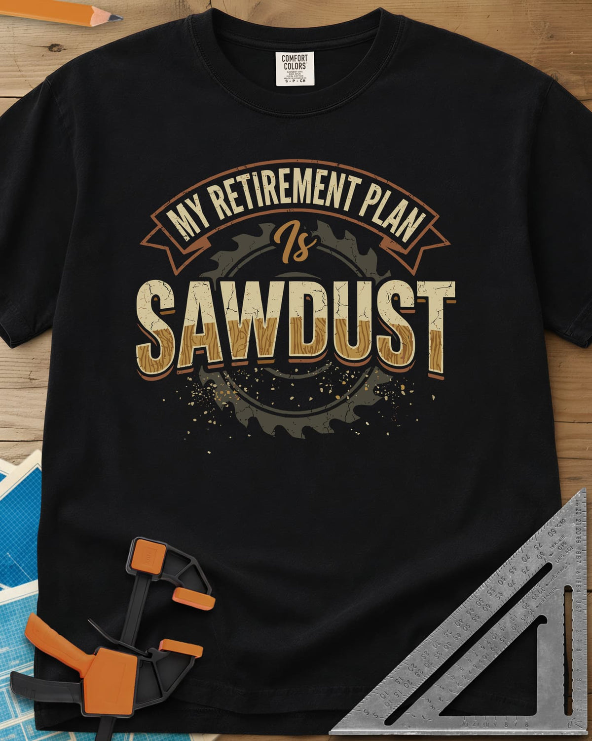 Sawdust Retirement heavyweight tee in Black, a ribbon banner over a saw blade, cracked wood-grain letters