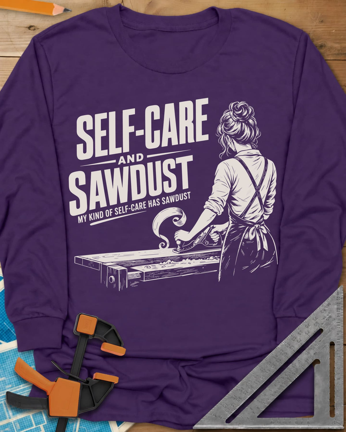 Self-Care & Sawdust long sleeve shirt in Purple, a woman at a workbench running a hand plane, shaving curling up
