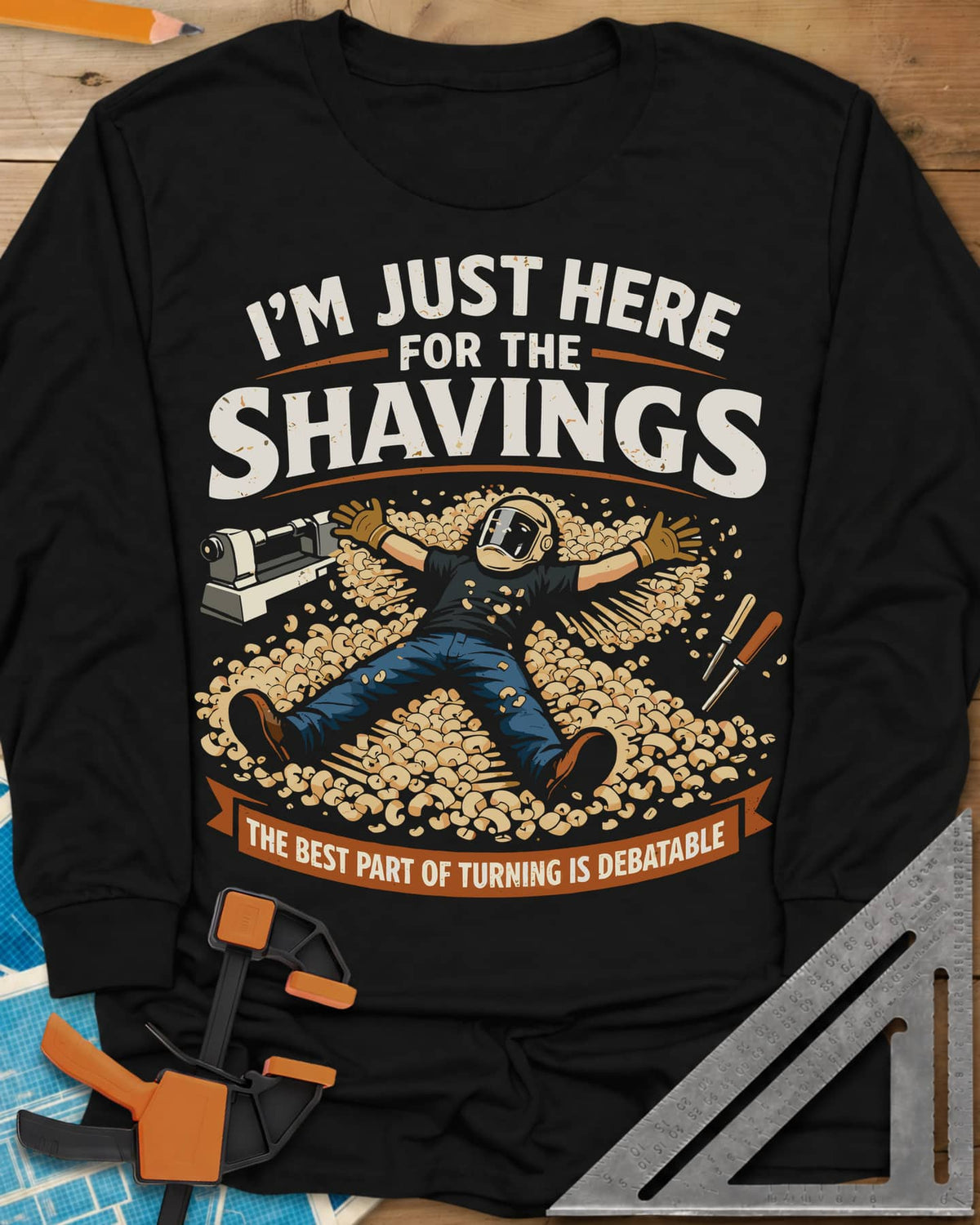 Shavings long sleeve shirt in Black, a turner in a face shield lying in a drift of wood shavings