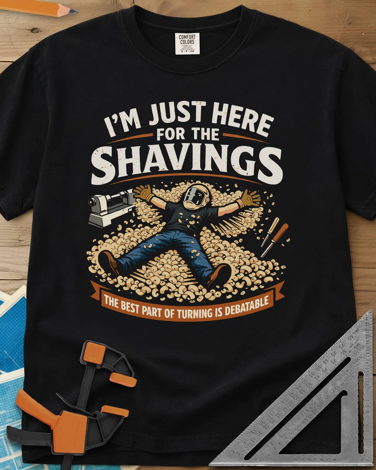 Shavings heavyweight tee in Black, a turner in a face shield lying in a drift of wood shavings