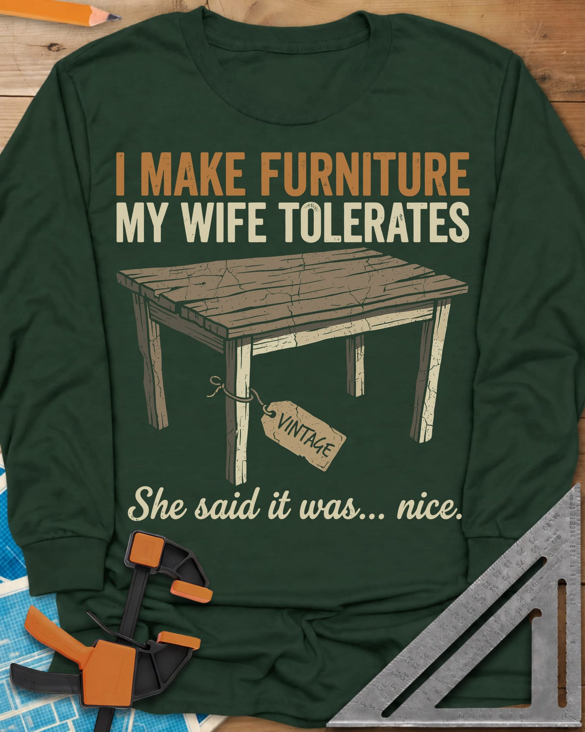 She Said It Was Nice long sleeve shirt in Forest Green, a weathered rustic table with a VINTAGE tag tied to one leg