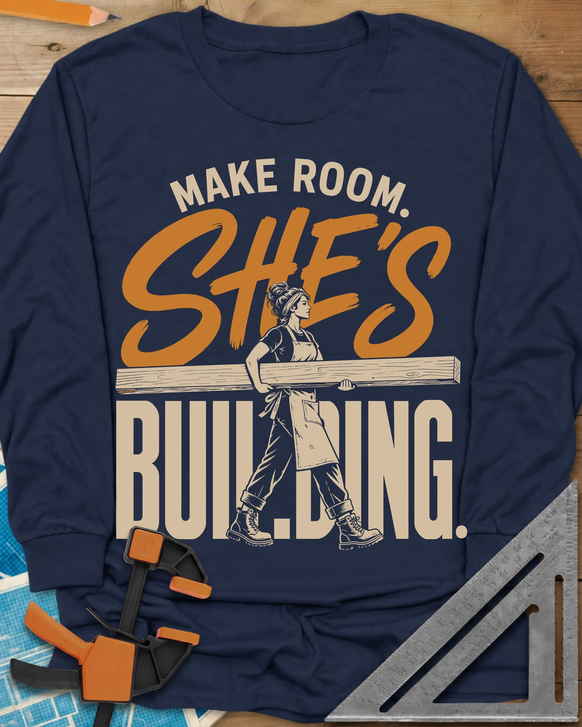 She'S Building long sleeve shirt in Navy, a woman in boots carrying a long beam through the lettering