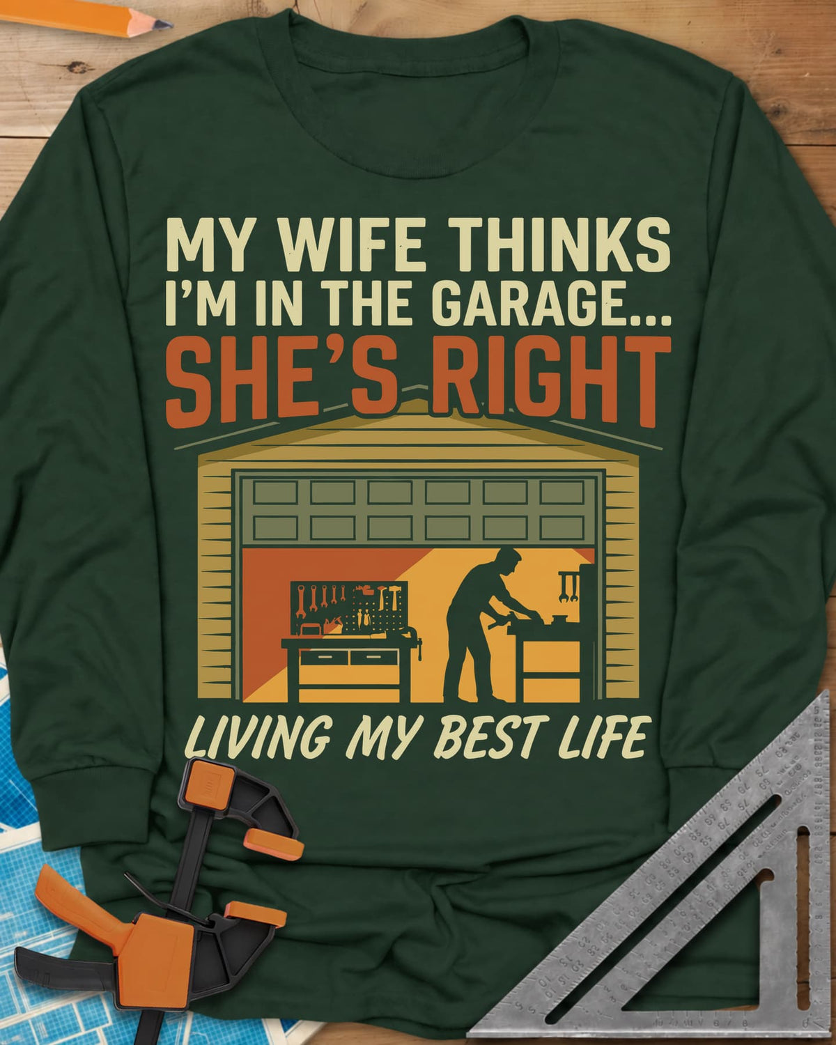 She’s Right long sleeve shirt in Forest Green, a man at his workbench in an open garage, tools on a pegboard