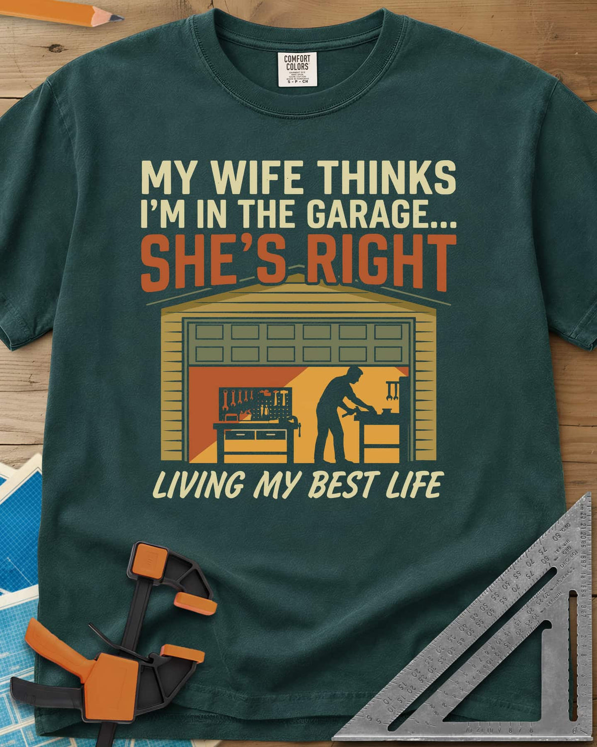 She’s Right heavyweight tee in Blue Spruce, a man at his workbench in an open garage, tools on a pegboard