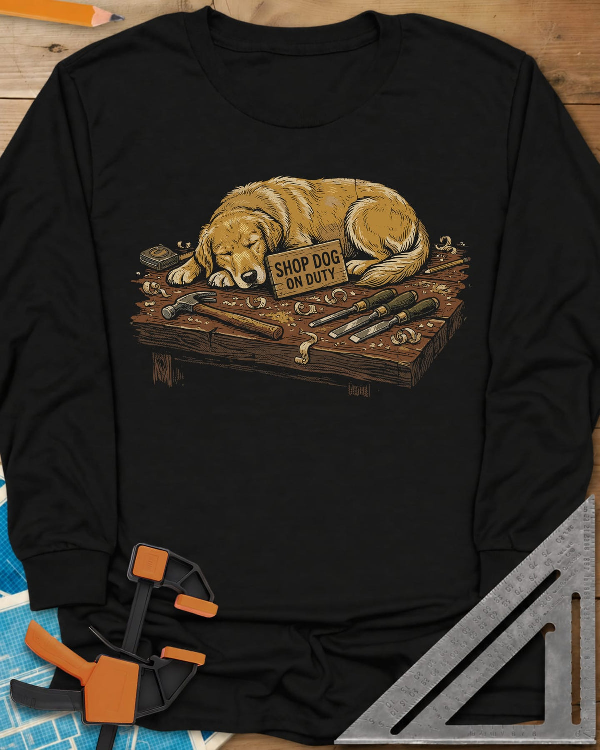 Shop Dog On Duty long sleeve shirt in Black, a golden retriever asleep on a workbench beside tools and shavings