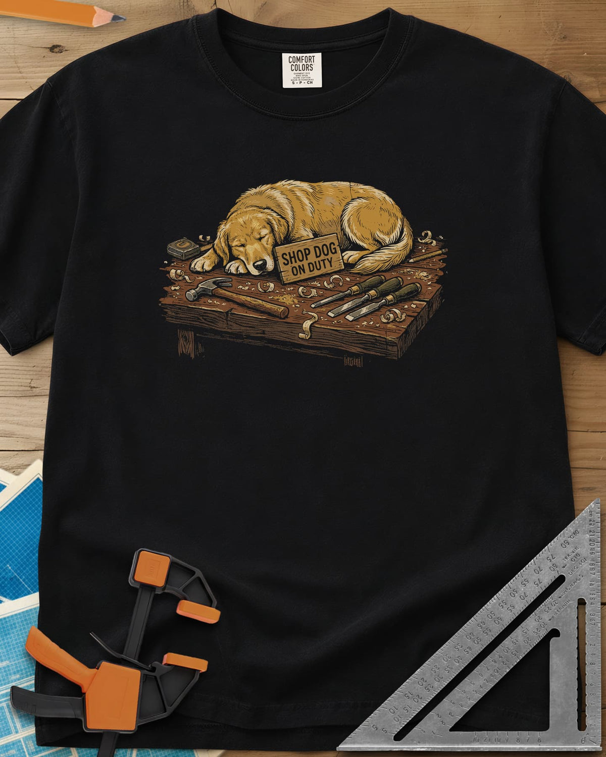 Shop Dog On Duty heavyweight tee in Black, a golden retriever asleep on a workbench beside tools and shavings
