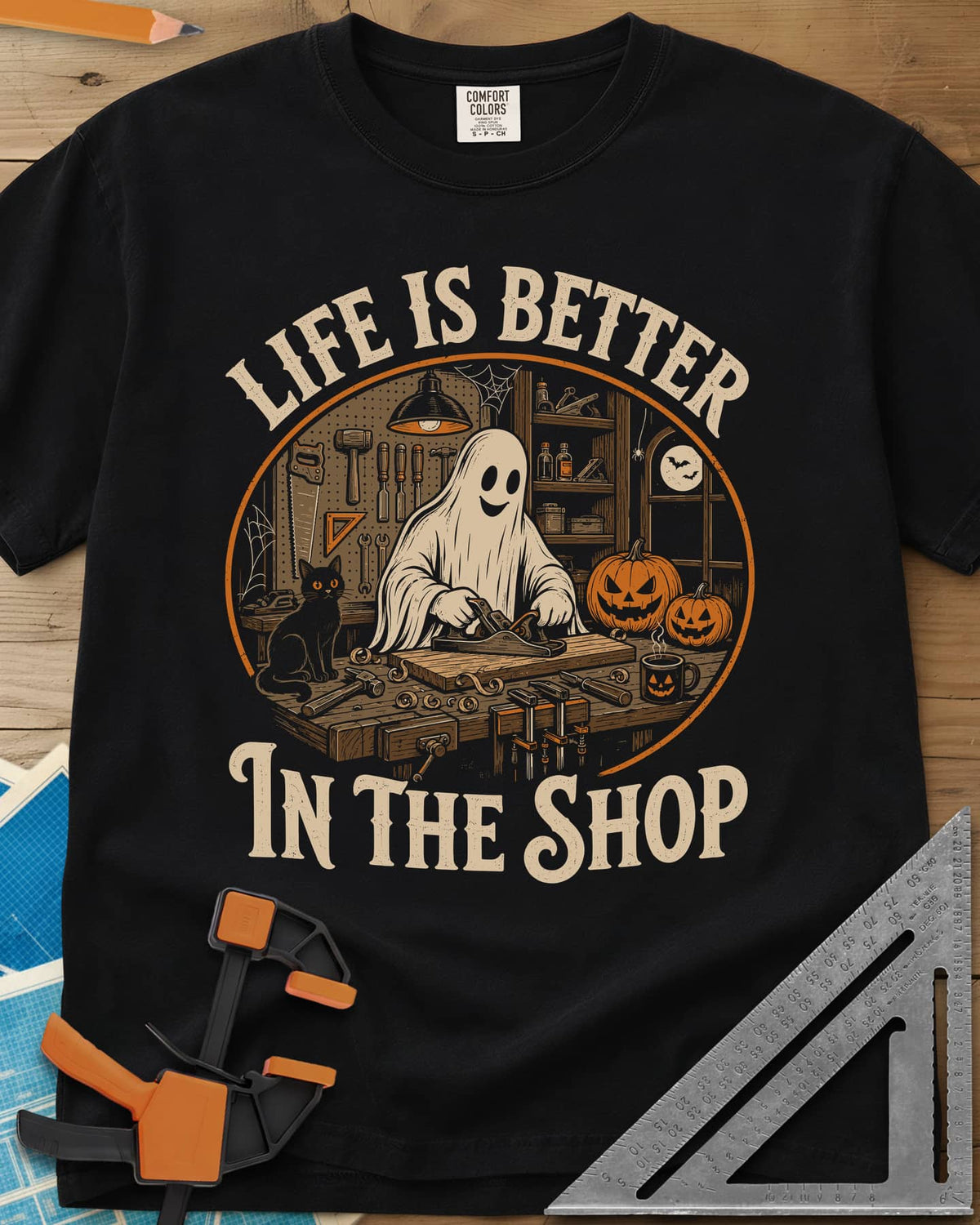 Shop Life heavyweight tee in Black, a smiling ghost planing a board beside a cat and pumpkins