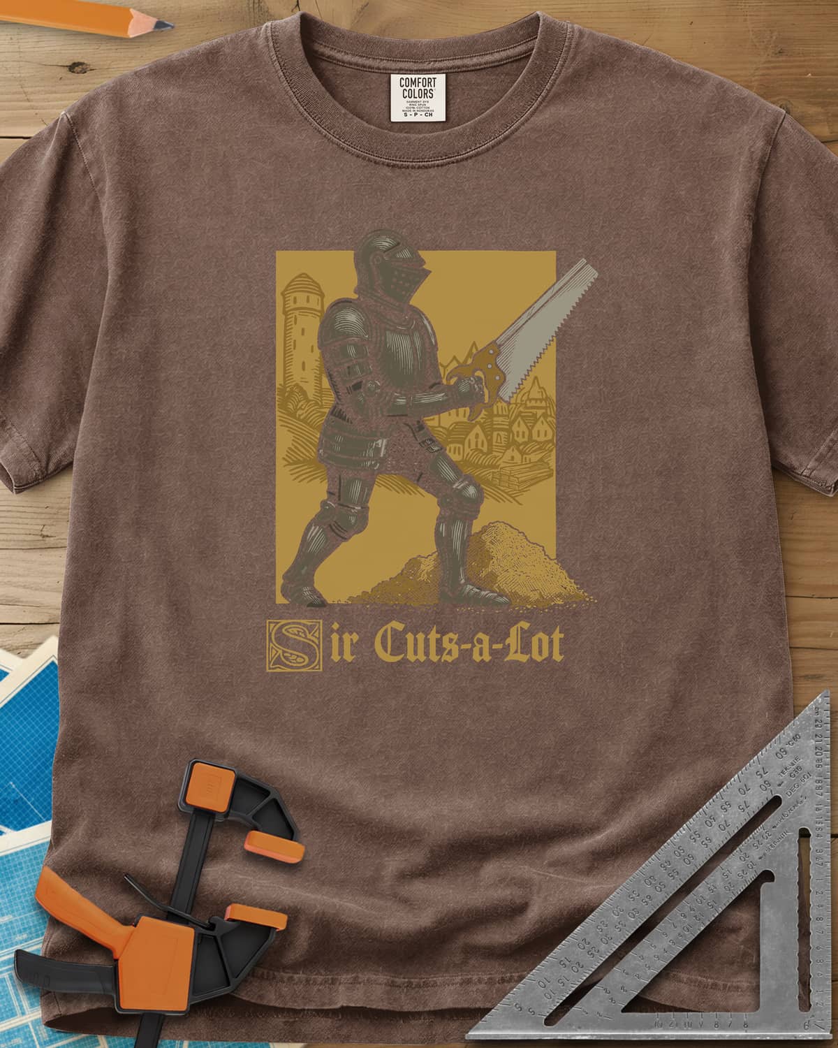 Sir Cuts A Lot heavyweight tee in Espresso, an armored knight with a handsaw and a mound of sawdust