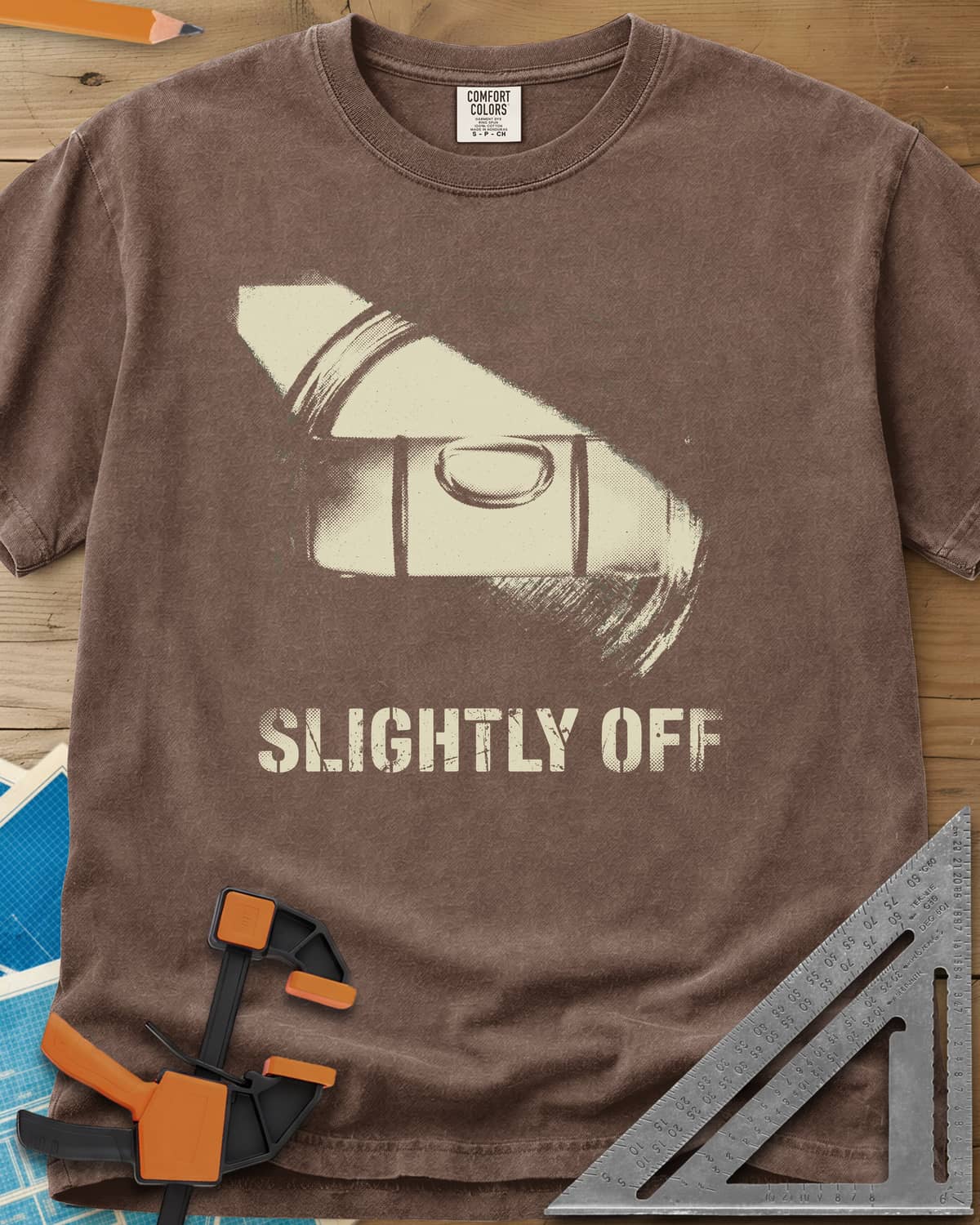 Slightly Off Level heavyweight tee in Espresso, a tilted spirit level and its bubble vial in grainy halftone