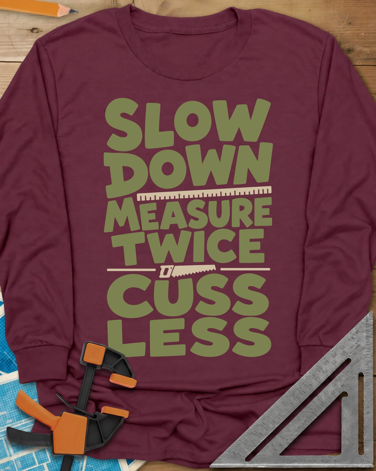 Slow Down Measure Twice long sleeve shirt in Maroon, stacked green letters with a ruler and a small handsaw between lines