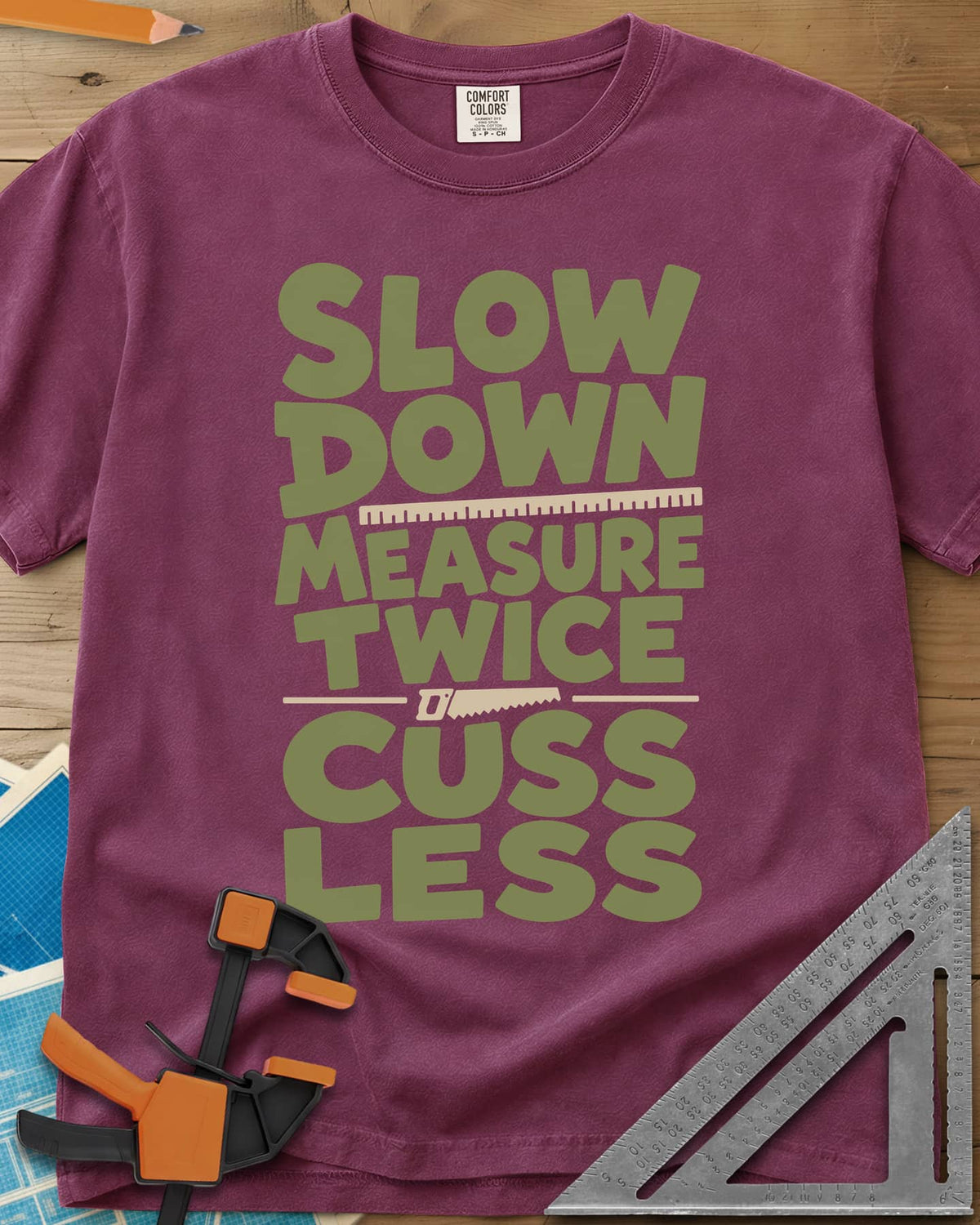 Slow Down Measure Twice heavyweight tee in Berry, stacked green letters with a ruler and a small handsaw between lines