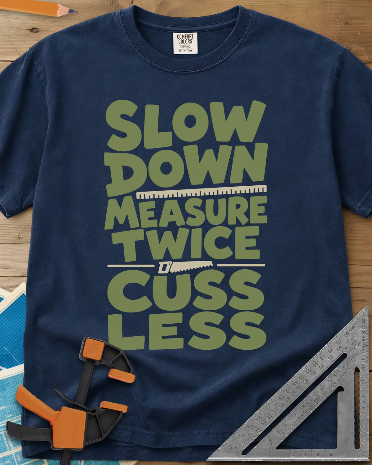 Slow Down Measure Twice heavyweight tee in Navy, stacked green letters with a ruler and a small handsaw between lines
