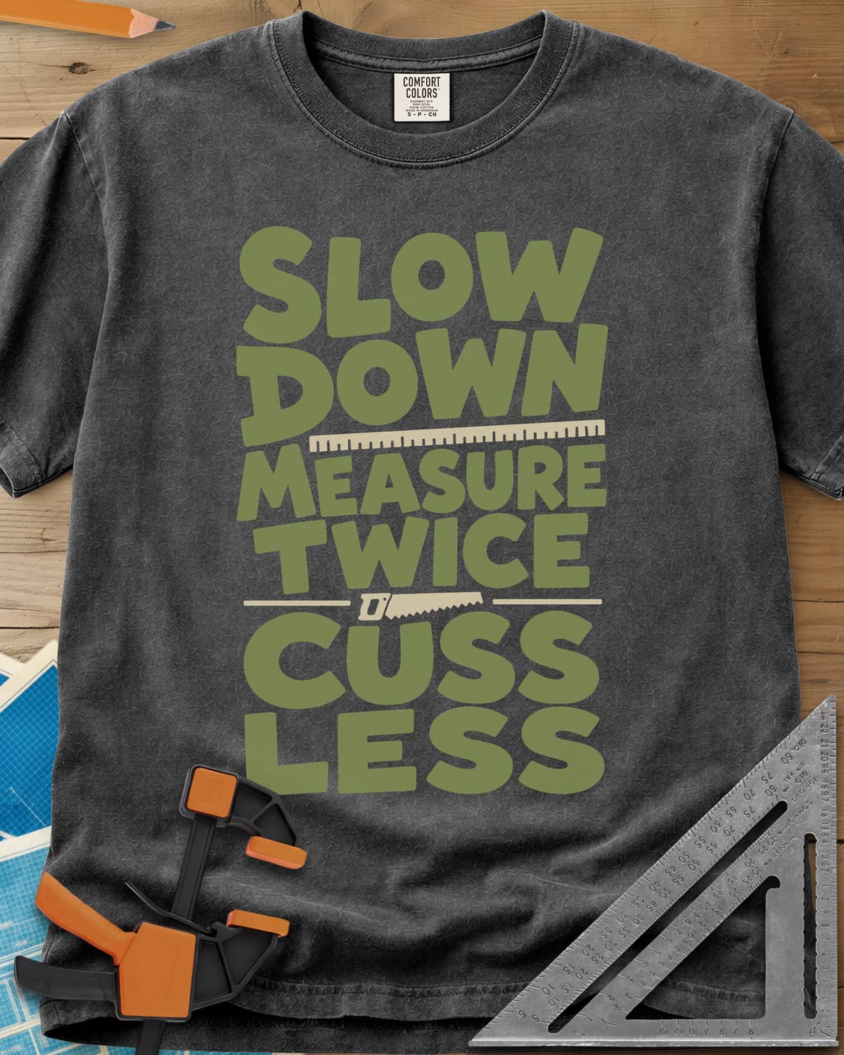 Slow Down Measure Twice heavyweight tee in Pepper, stacked green letters with a ruler and a small handsaw between lines