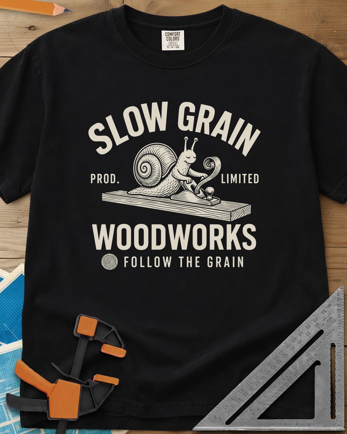 Slow Grain heavyweight tee in Black, a smiling snail planing a plank, one curl of shaving rising