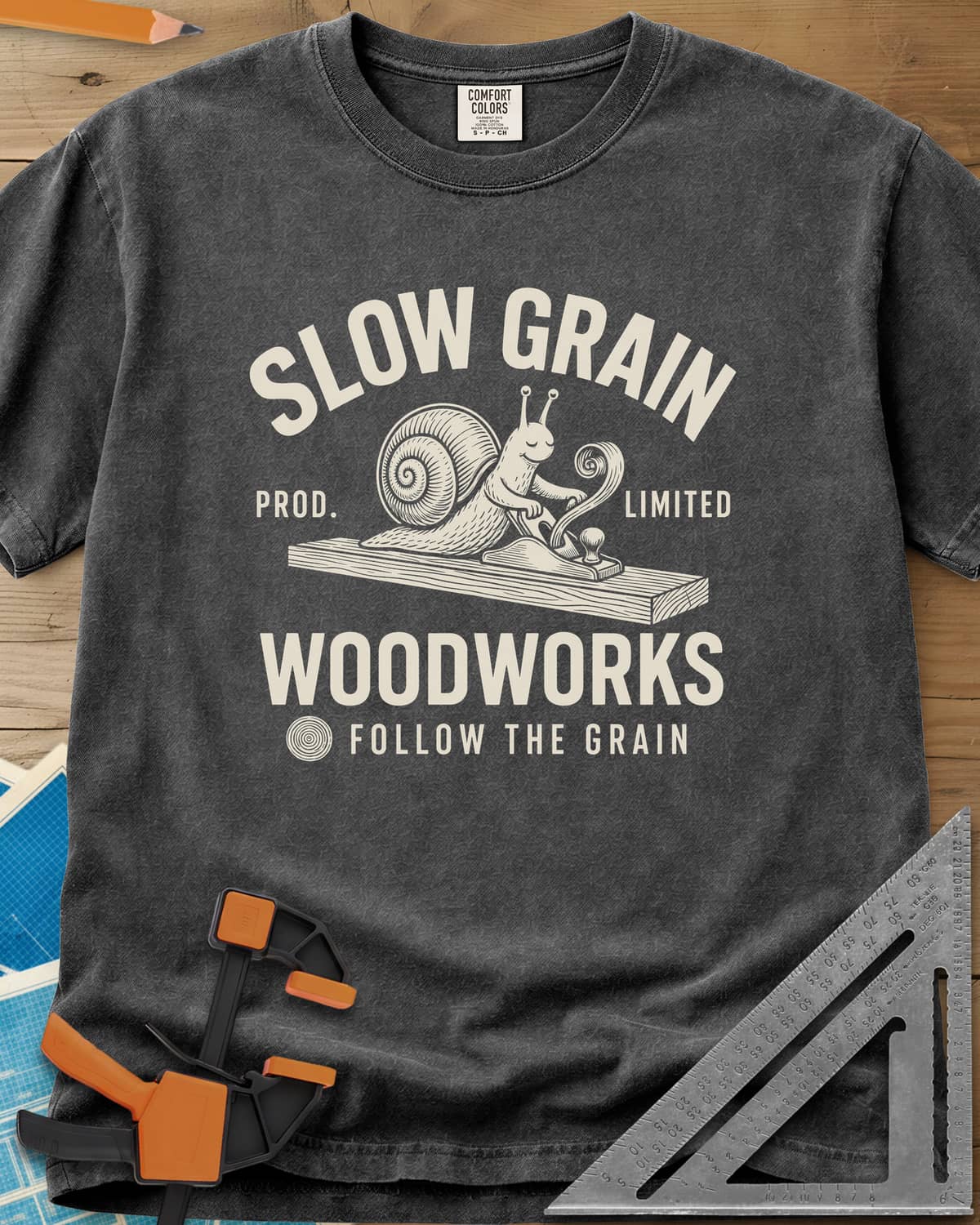 Slow Grain heavyweight tee in Pepper, a smiling snail planing a plank, one curl of shaving rising