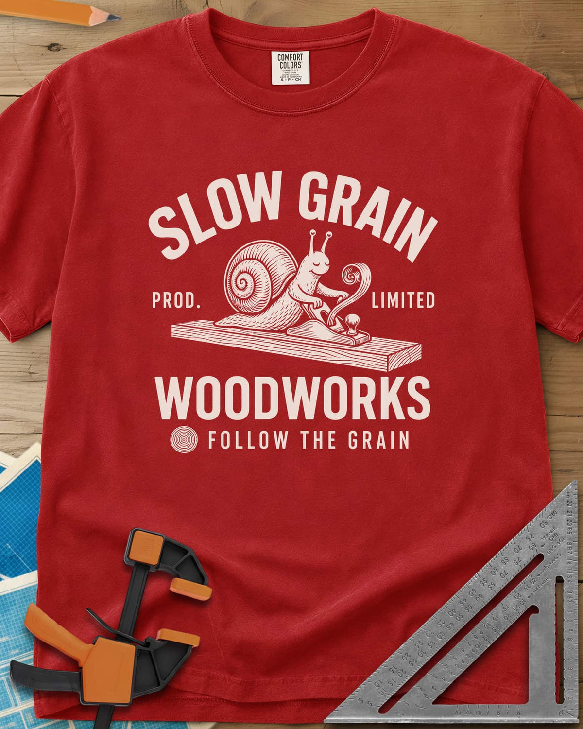 Slow Grain heavyweight tee in Red, a smiling snail planing a plank, one curl of shaving rising