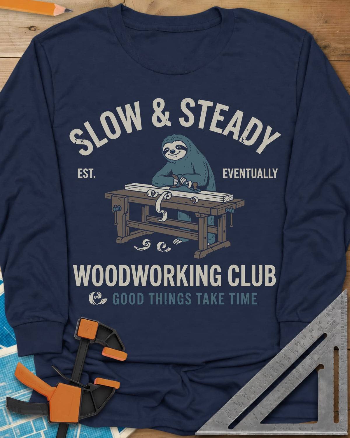 Slow Steady long sleeve shirt in Navy, a blue sloth planing a board at a workbench, shavings falling