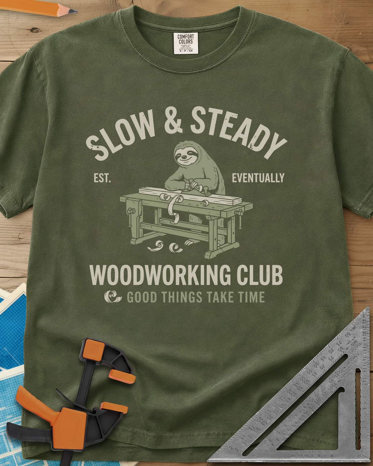 Slow Steady heavyweight tee in Hemp, a blue sloth planing a board at a workbench, shavings falling