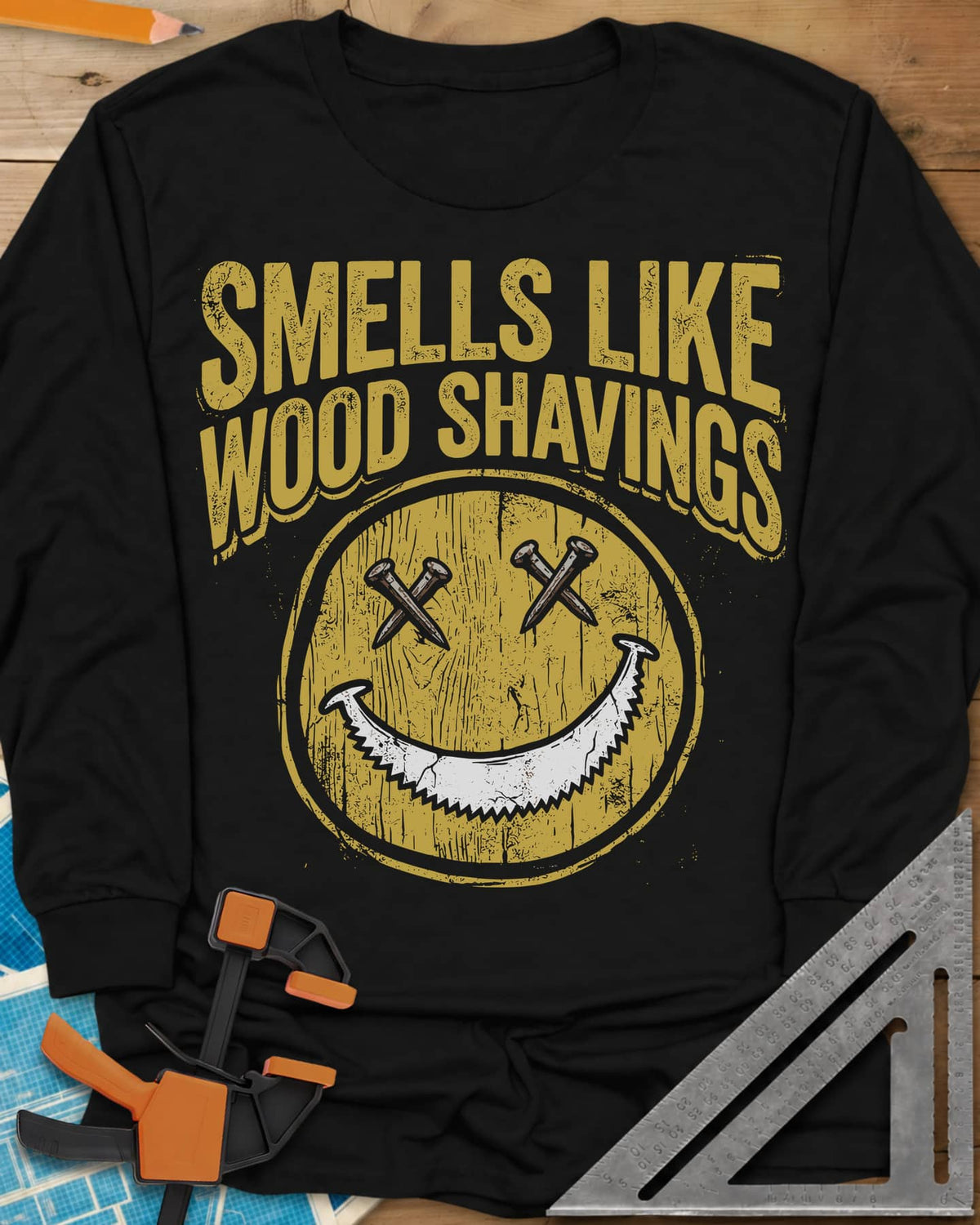 Smells Like Wood Shavings long sleeve shirt in Black, a worn yellow smiley with nails for eyes and a saw blade grin