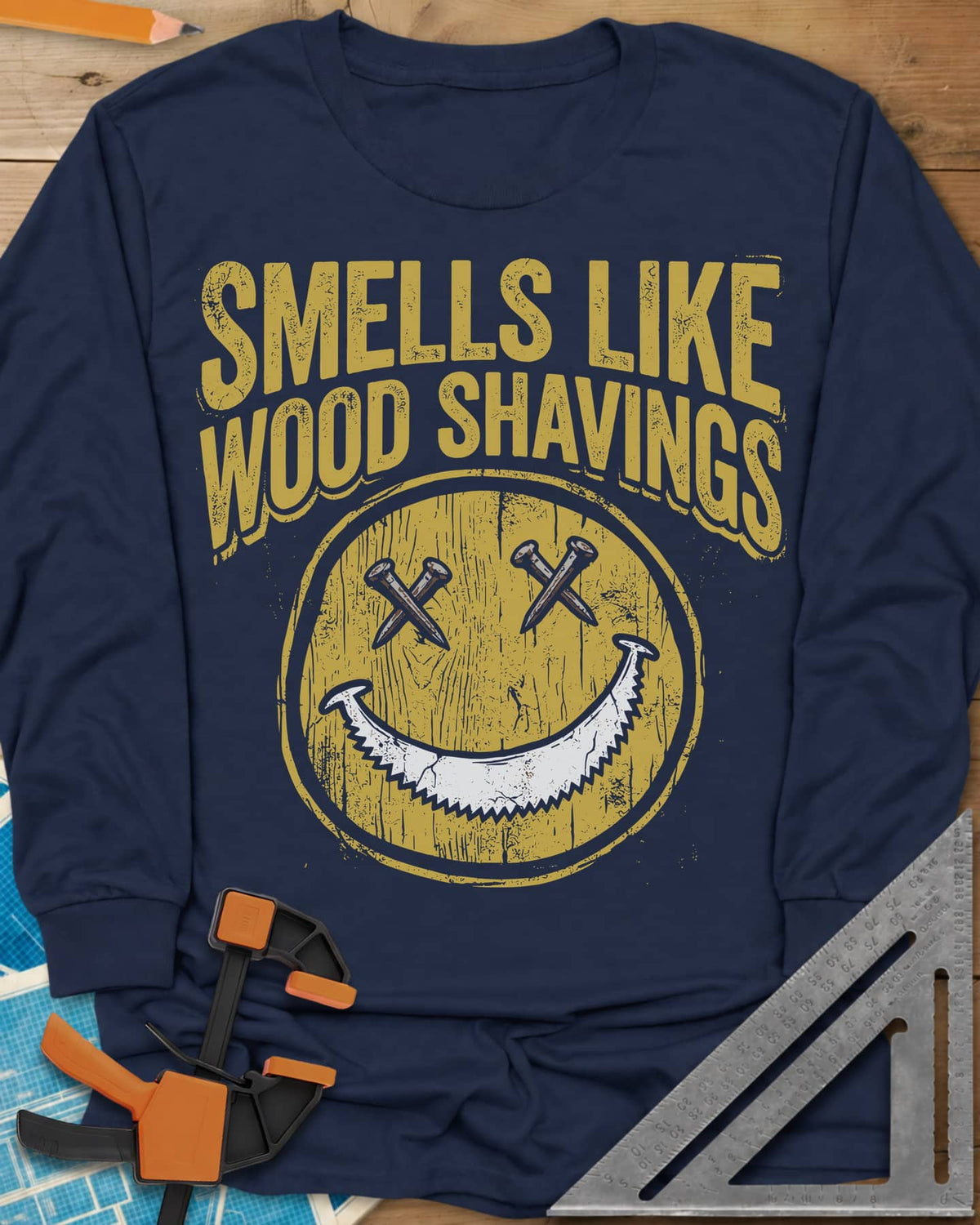 Smells Like Wood Shavings long sleeve shirt in Navy, a worn yellow smiley with nails for eyes and a saw blade grin