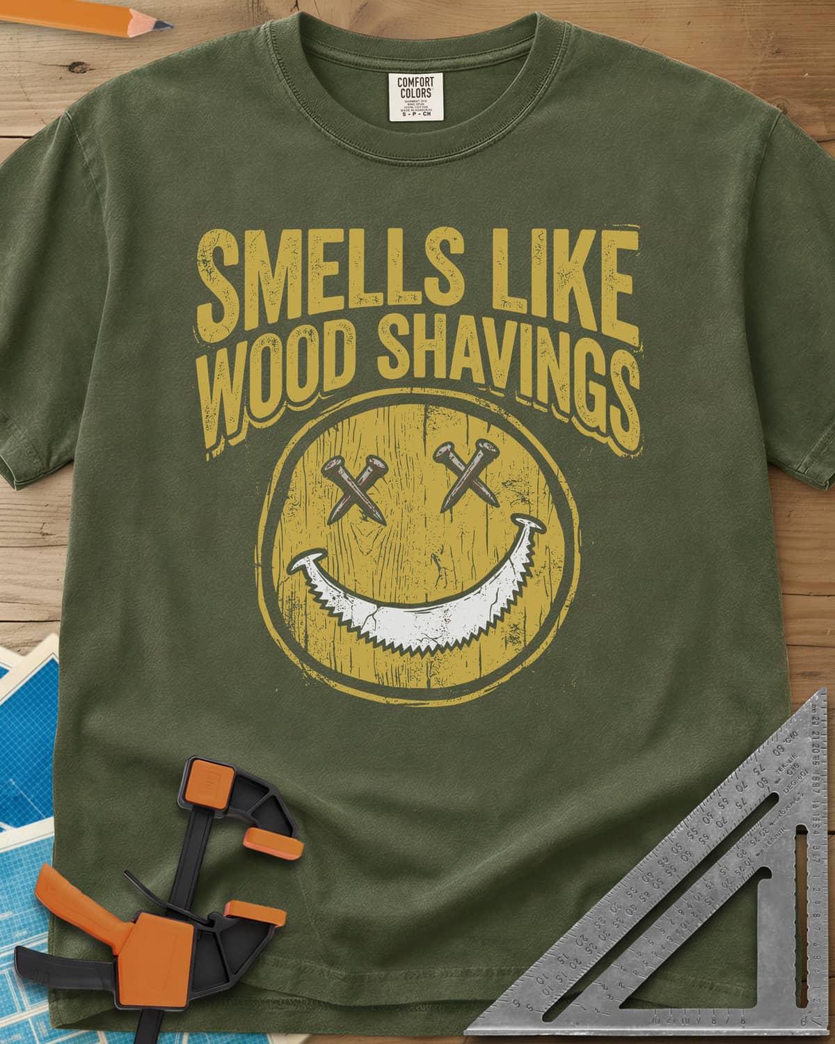 Smells Like Wood Shavings heavyweight tee in Hemp, a worn yellow smiley with nails for eyes and a saw blade grin